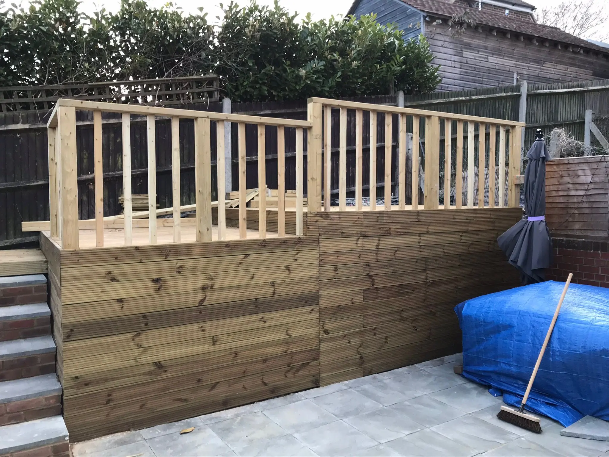 A picture of a raised wooden decking structure with timber railings under construction in a garden