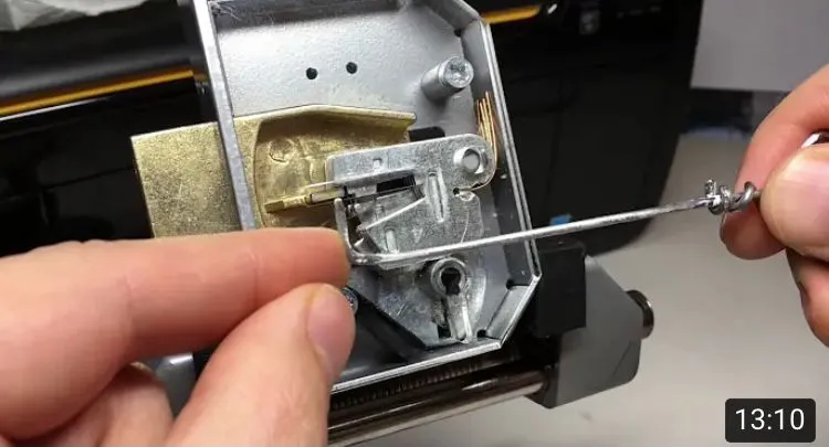 Close-up of a locksmith's hands working on the internal components of a door lock with a metal tool, showcasing a precise technique.