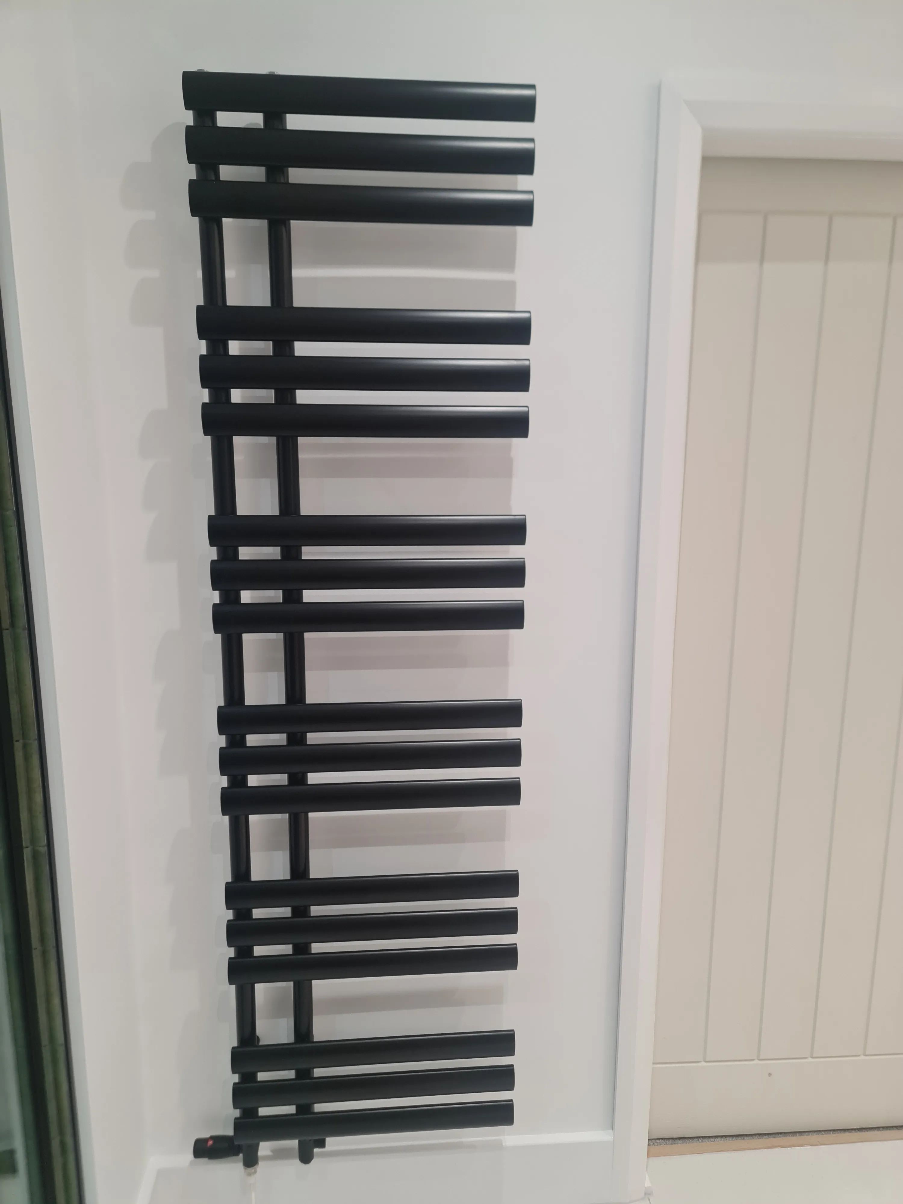 Bespoke matte black designer heated towel rail installed by Sands & Vossen in a luxury bathroom renovation.