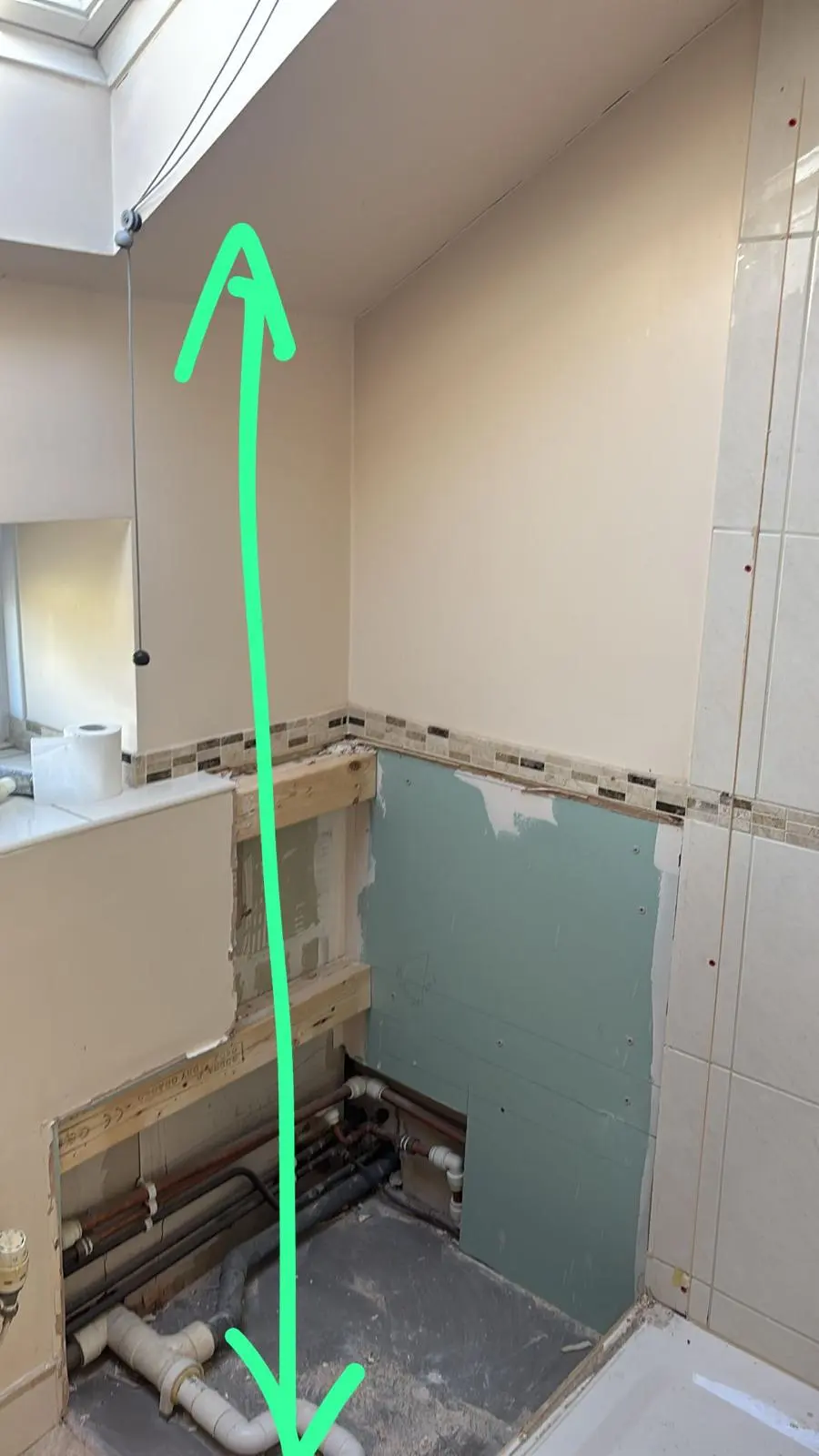 Bathroom renovation in progress showing exposed pipes, timber framing, and plasterboard