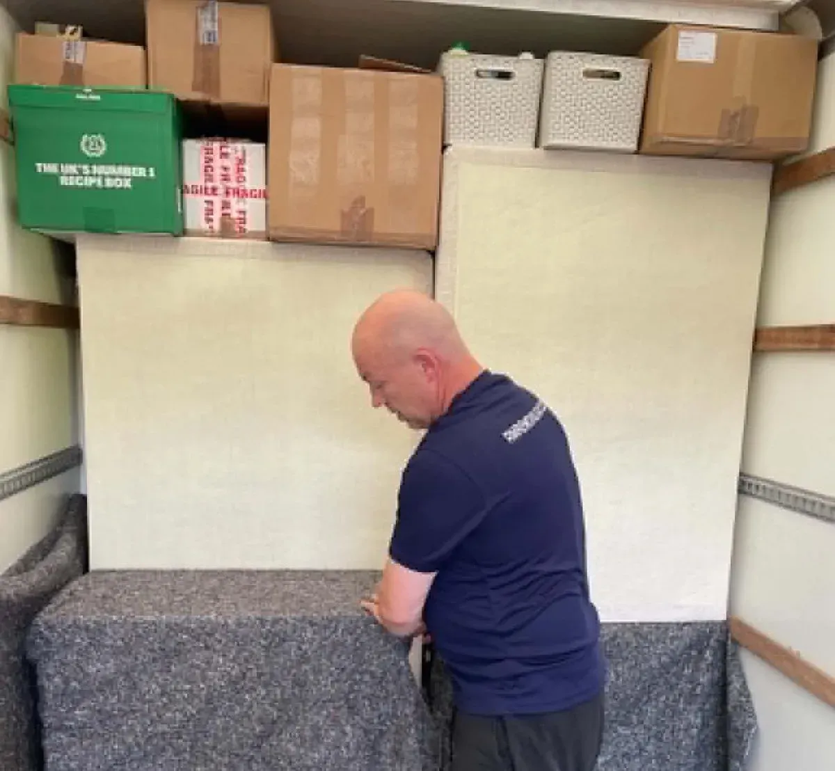 RM Removals team member packing household goods and furniture using protective blankets inside a removal van