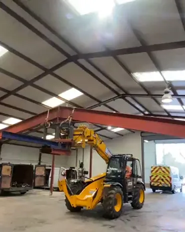 JCB telehandler lifting structural steel beams in a workshop for RA Steelworks Services LTD
