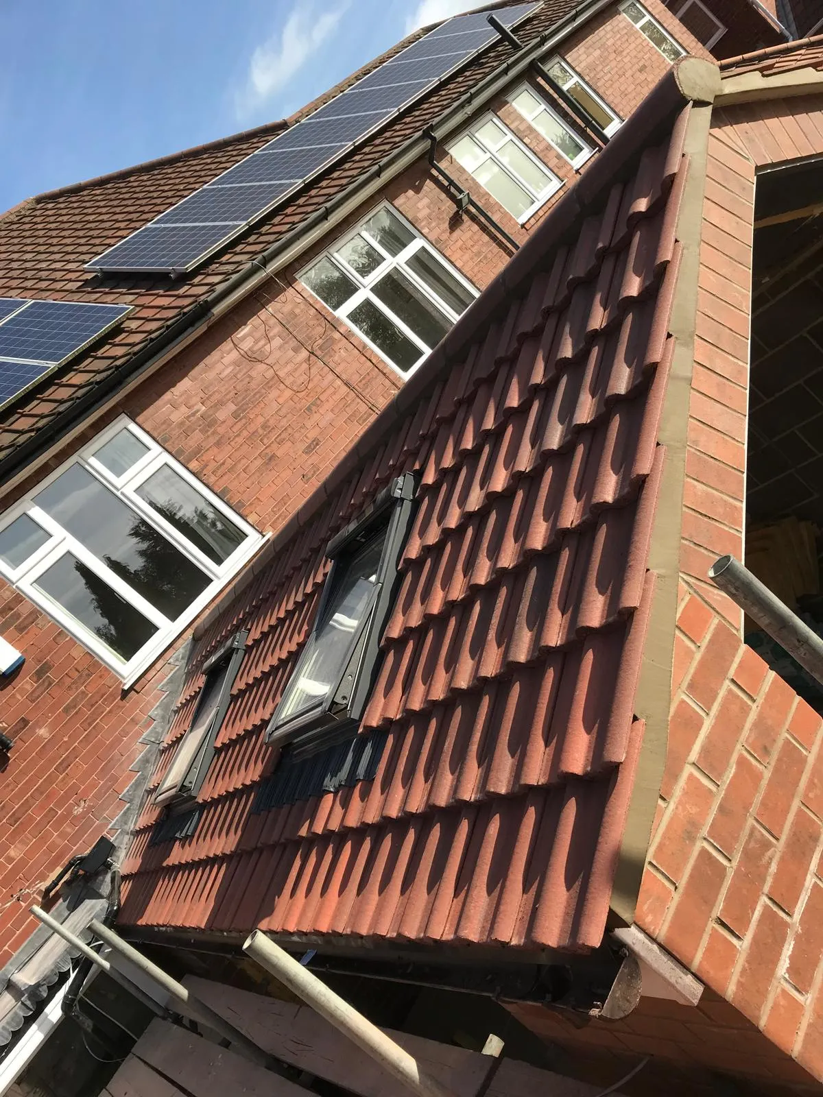 Newly installed or repaired red tiled pitched roof with Velux windows and solar panels on a brick house, demonstrating DSR Roofing York's quality workmanship.