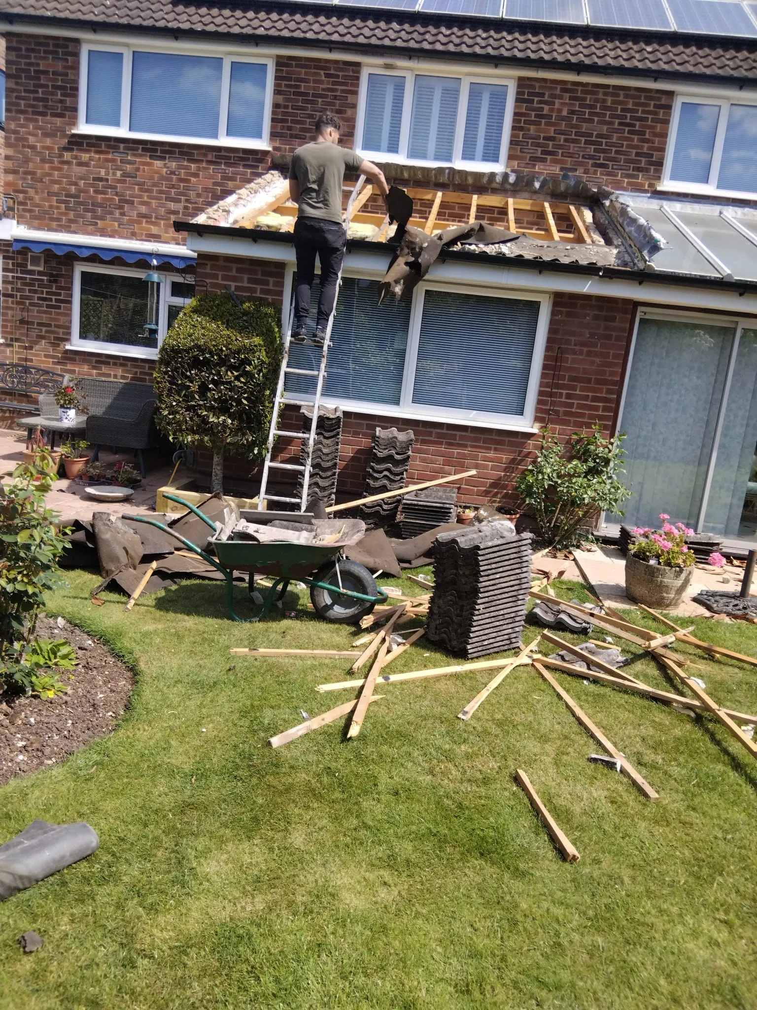 Roof replacement and structural strip down on a residential extension showing exposed roof timbers and stacked tiles