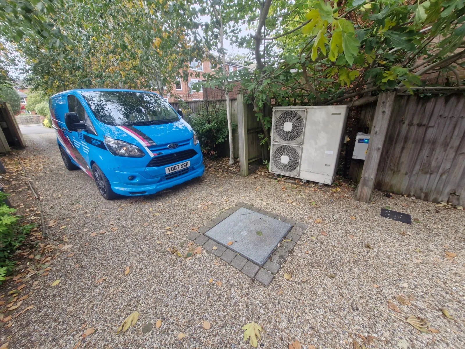 Roberts Drainage Ltd service van parked on a driveway next to a manhole cover, providing drainage services in Cambridgeshire