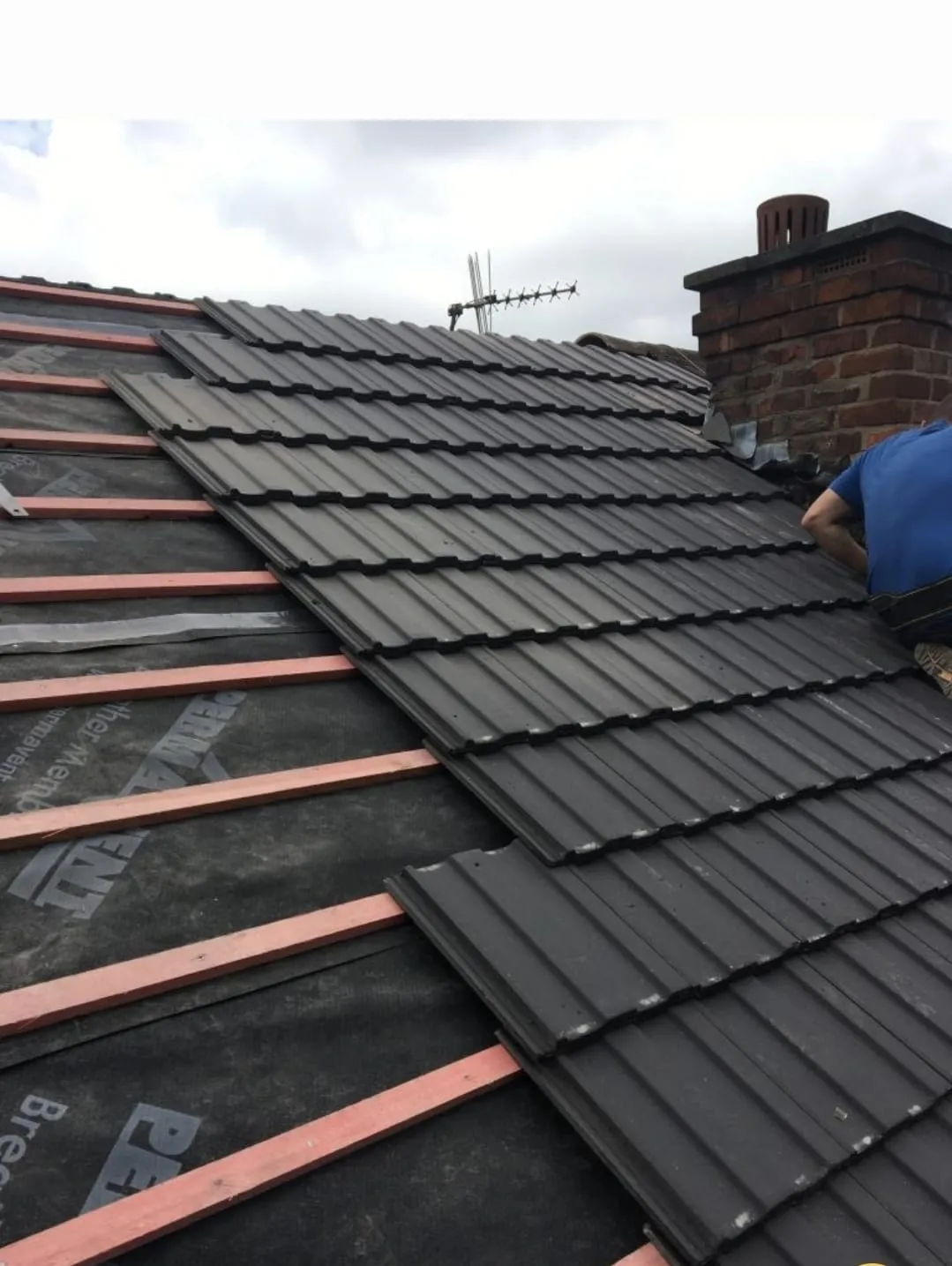 A professional roofer laying new tiles on a residential pitched roof during a re-roofing project in Cornwall.
