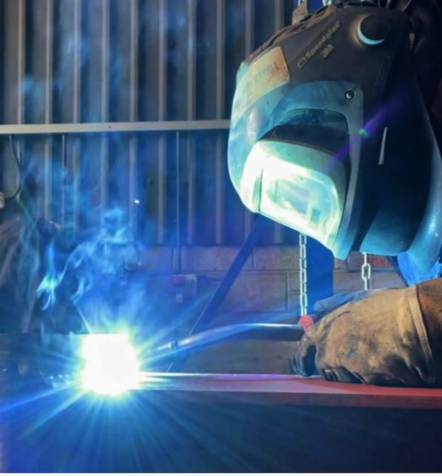 Coded welder in Southampton performing structural steel fabrication with a welding torch and protective helmet.
