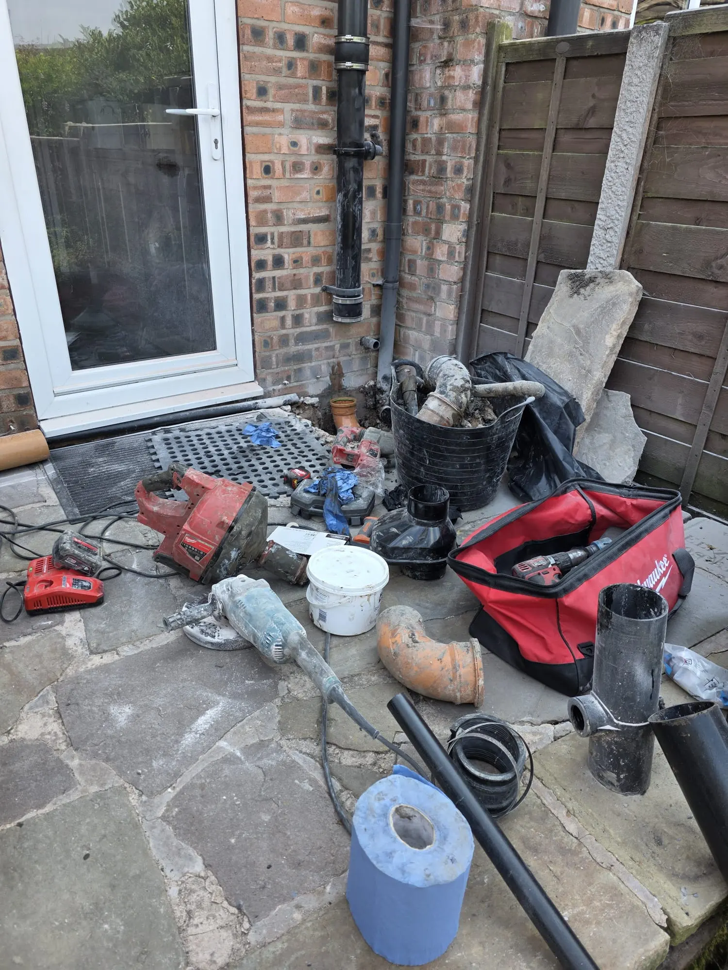 Drainage Cheshire tools and equipment laid out during a domestic drain excavation and pipe replacement job on a residential stone patio.
