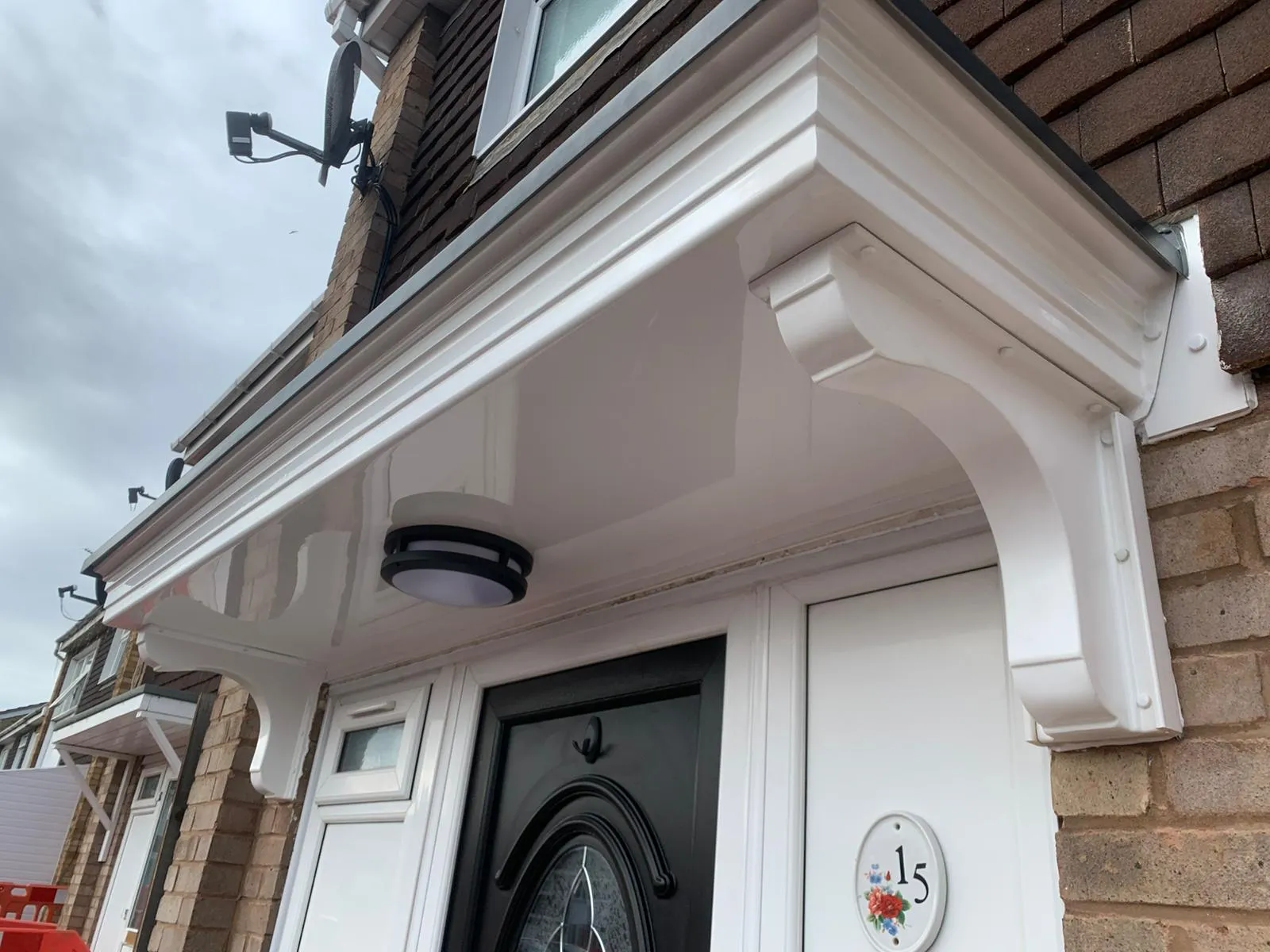 Newly installed white uPVC fascias, soffits, and decorative door canopy on a residential home in Gloucestershire.