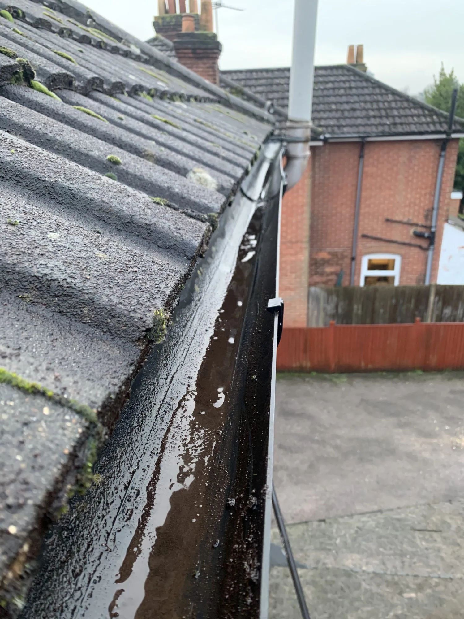 Newly installed black uPVC guttering on a tiled roof