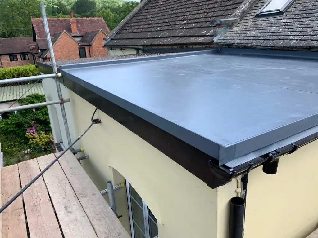 Expert new flat roof installation with a grey weatherproof membrane and black guttering