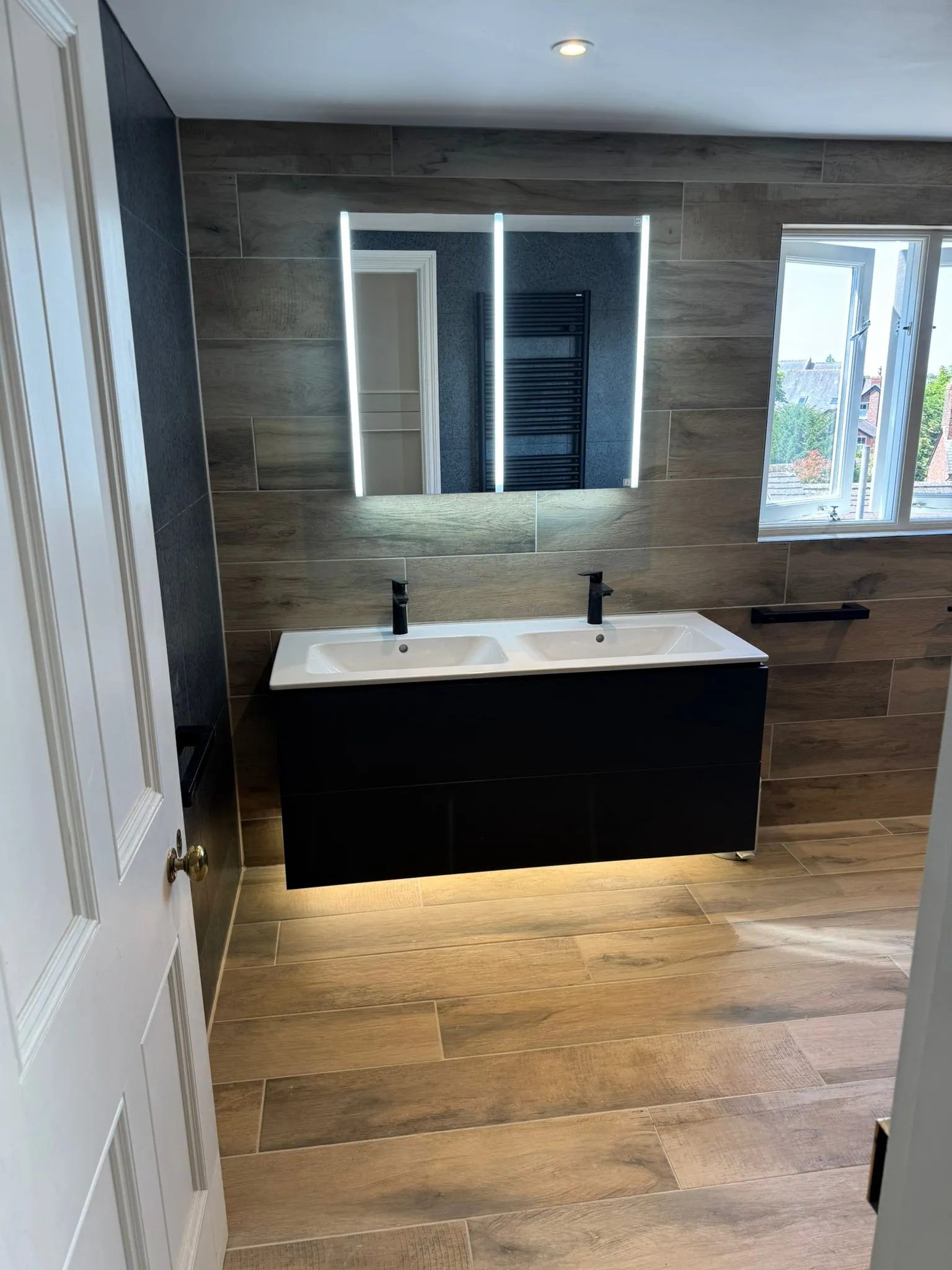 Modern bathroom installation with a double vanity and illuminated mirror by Redorr Heating & Cooling Services Ltd.