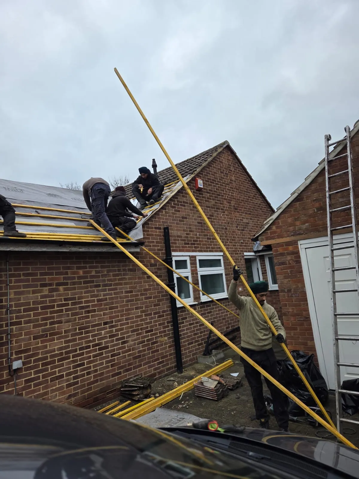 Professional roofers performing a new roof installation on a residential house in Cornwall.