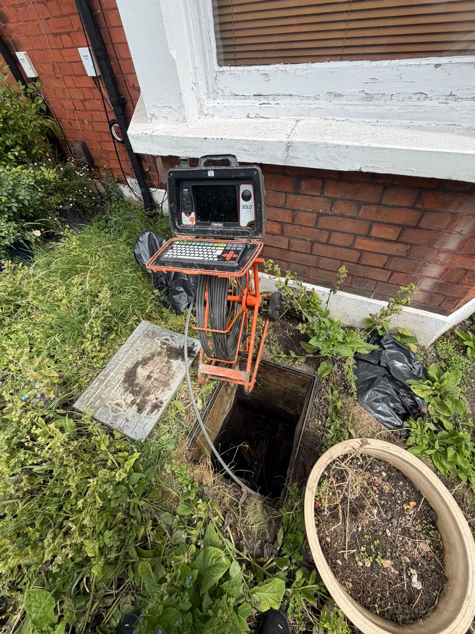 Specialist CCTV drain survey camera equipment set up over an open inspection chamber at a domestic property in Slough