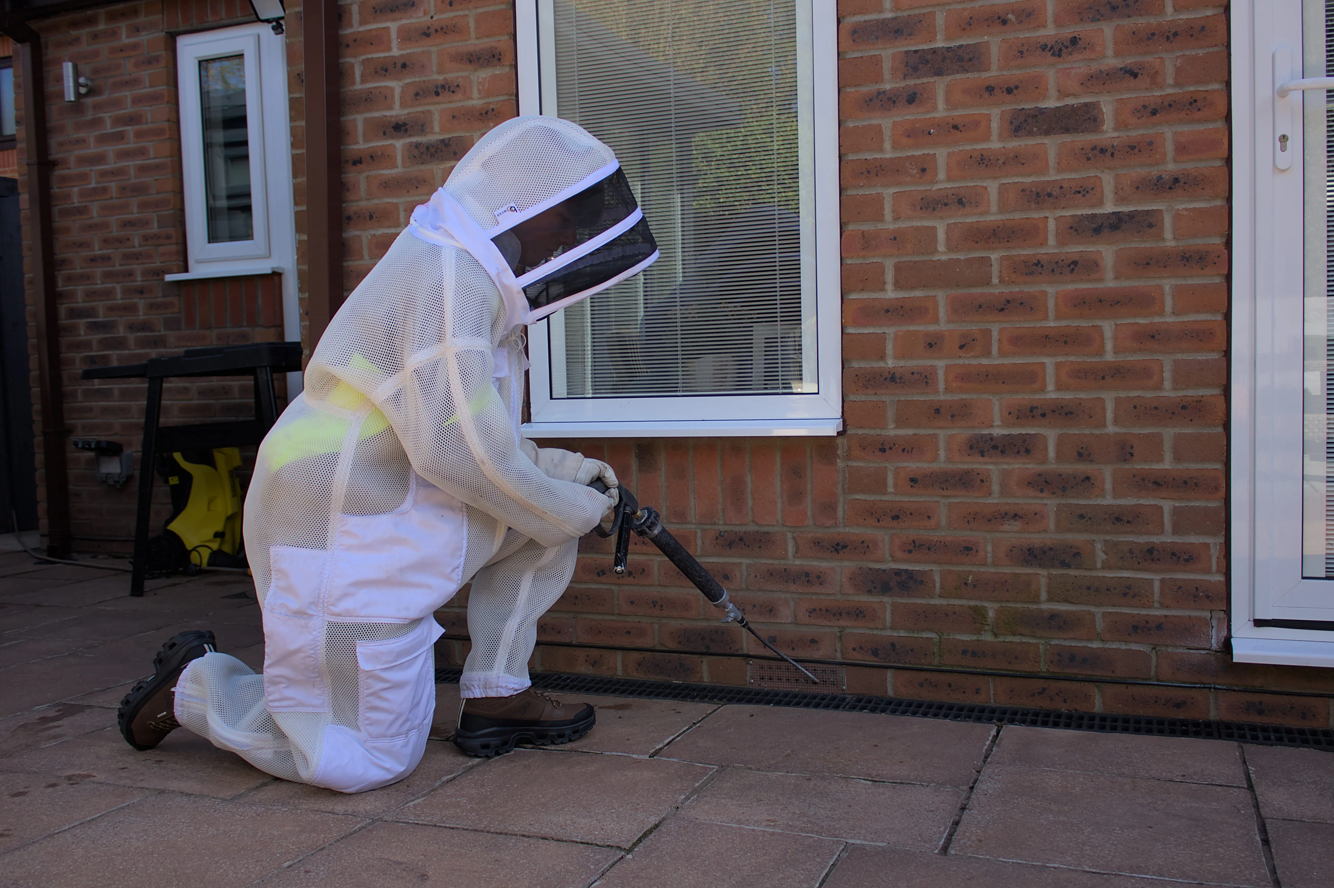 Professional wasp nest removal in Harrogate by a technician in a protective suit treating an external vent