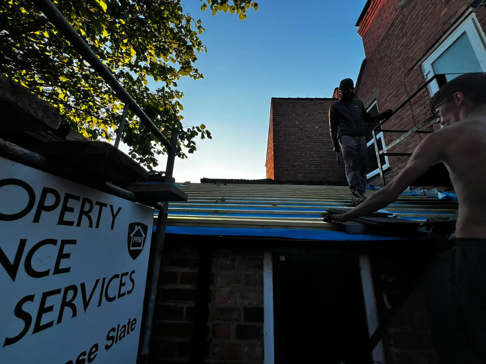 Pendle Property Maintenance roofers laying slate tiles on a pitched roof