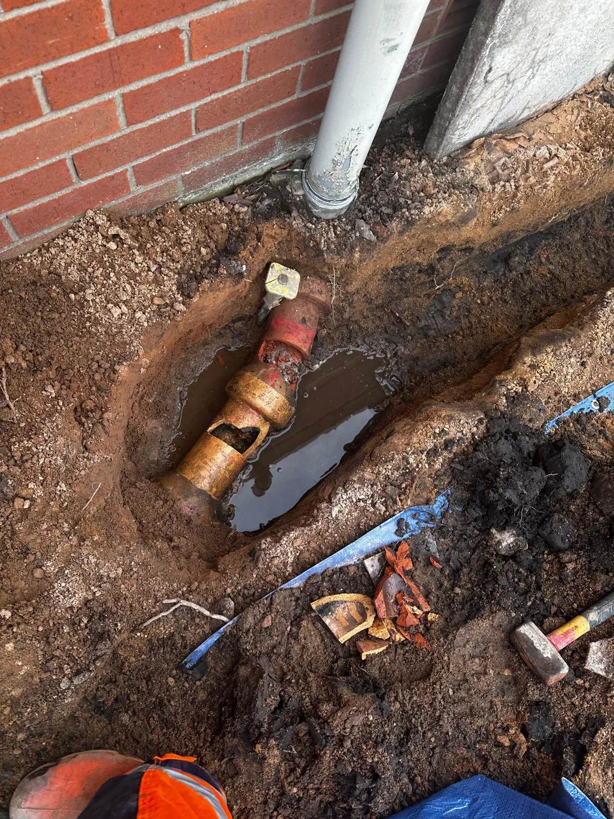 Damaged drain pipe exposed in a trench awaiting repair by Drain Magic.