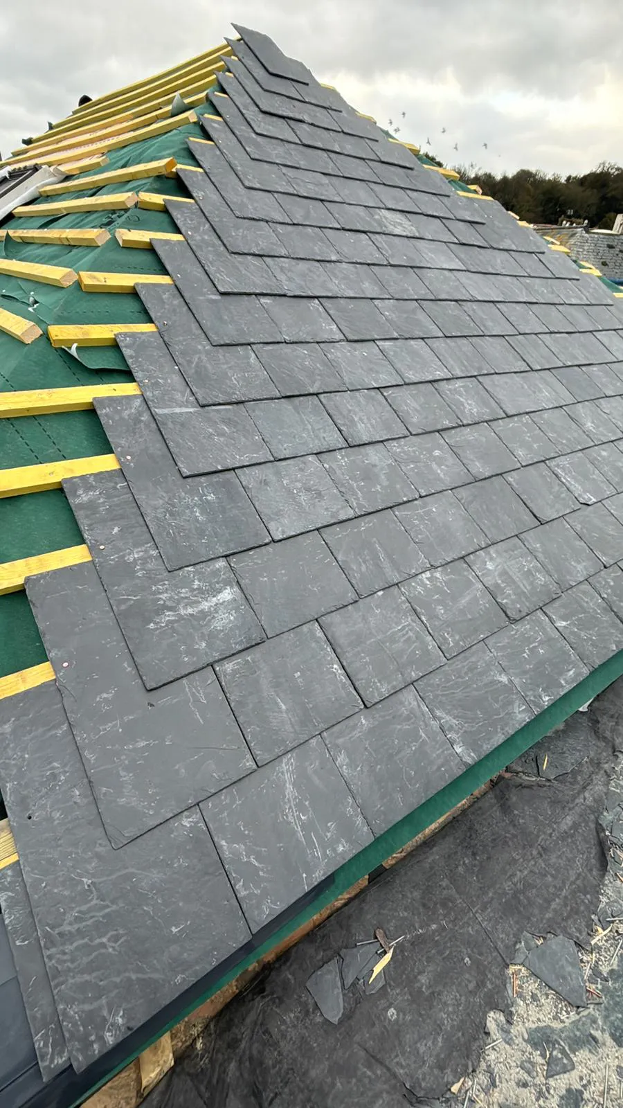 Pitched slate roof installation in progress over treated timber battens and breathable underlay