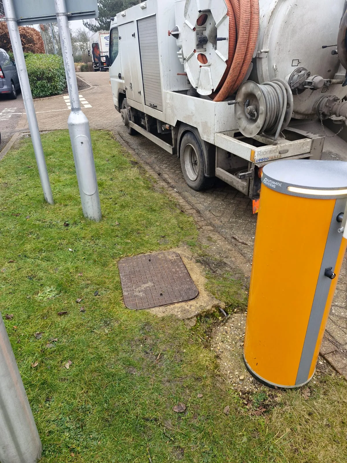 A professional drainage tanker and jetting vehicle parked next to a manhole cover for commercial drainage maintenance.