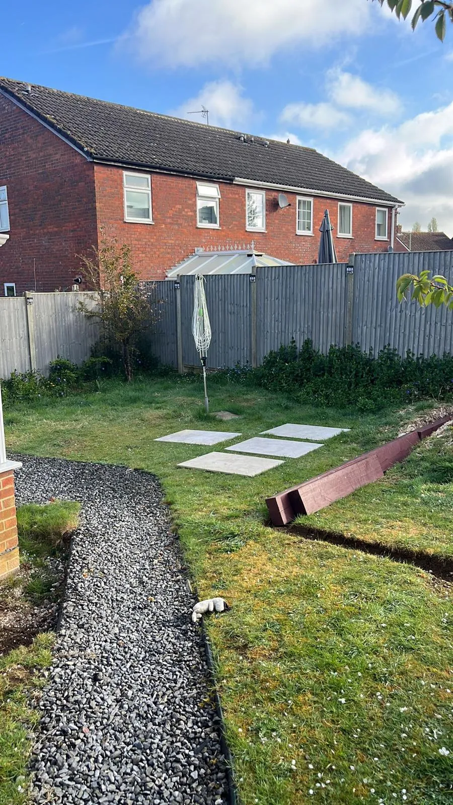 Landscaping in progress with a new gravel path, paving stones, and garden edging trench, set in a residential backyard in Tadley.