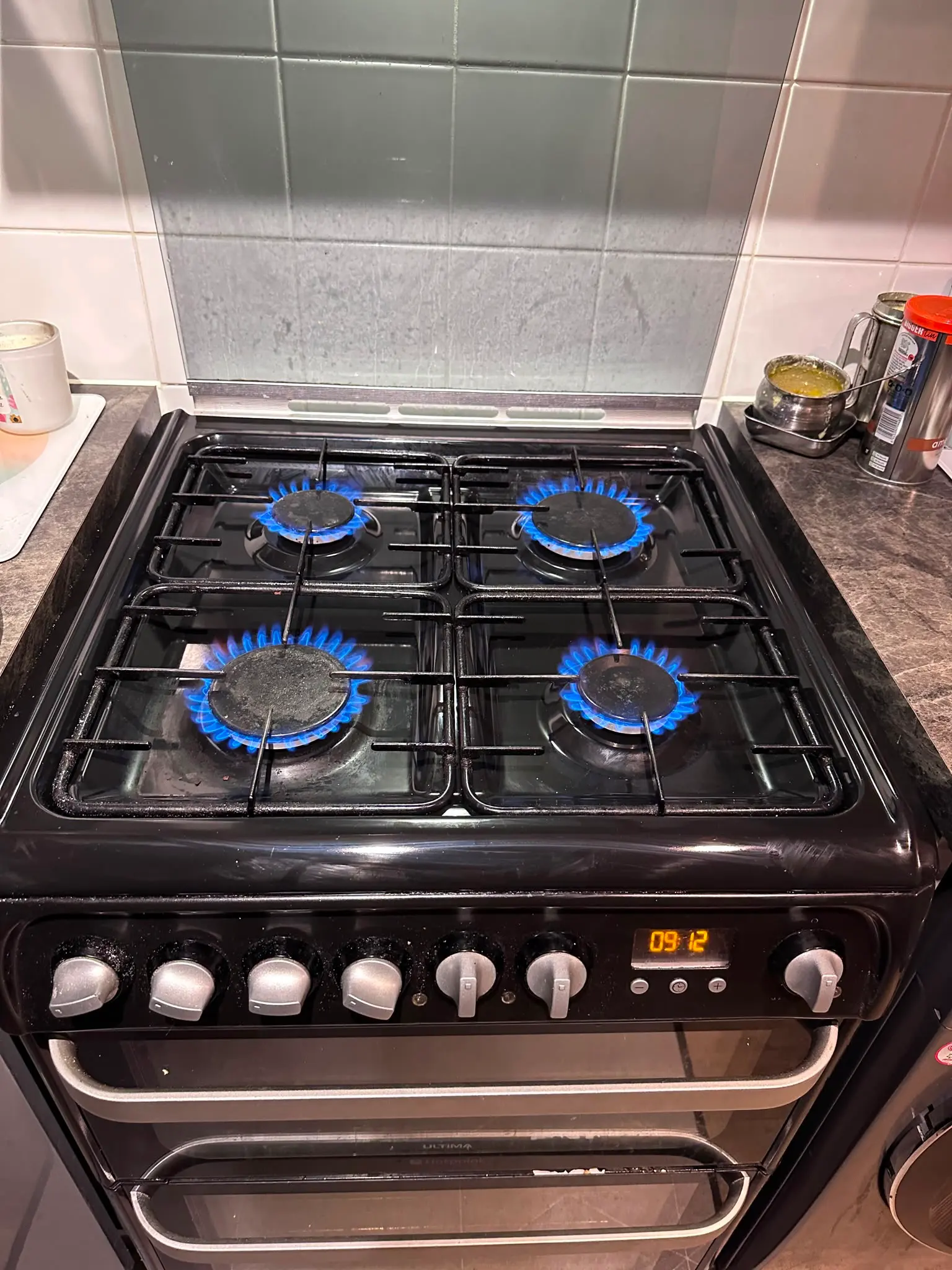 A black freestanding gas cooker with four active blue flames on the hob, highlighting safe gas appliance installation
