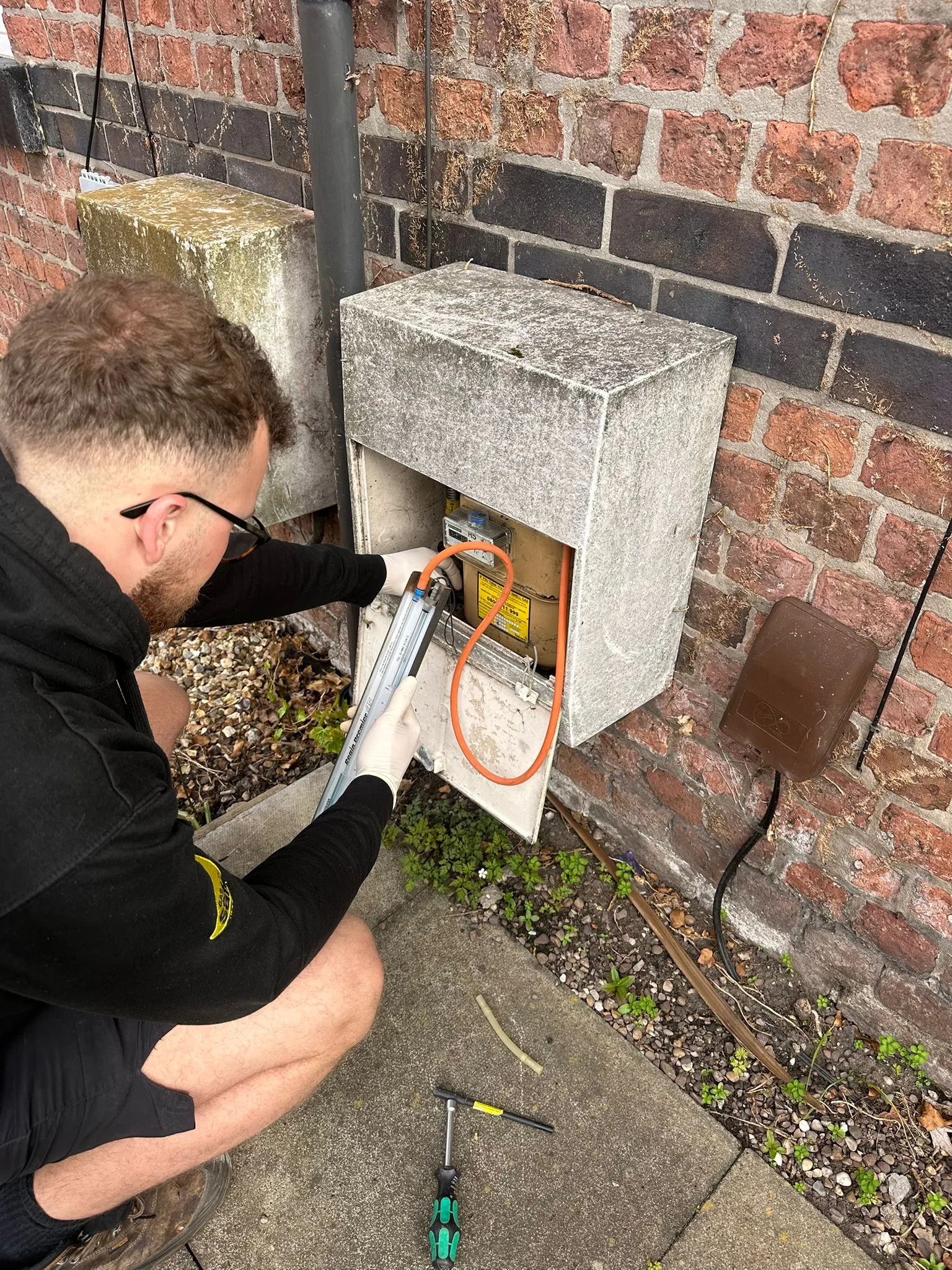 A Gas Safe engineer inspecting an external gas meter box during a safety check.