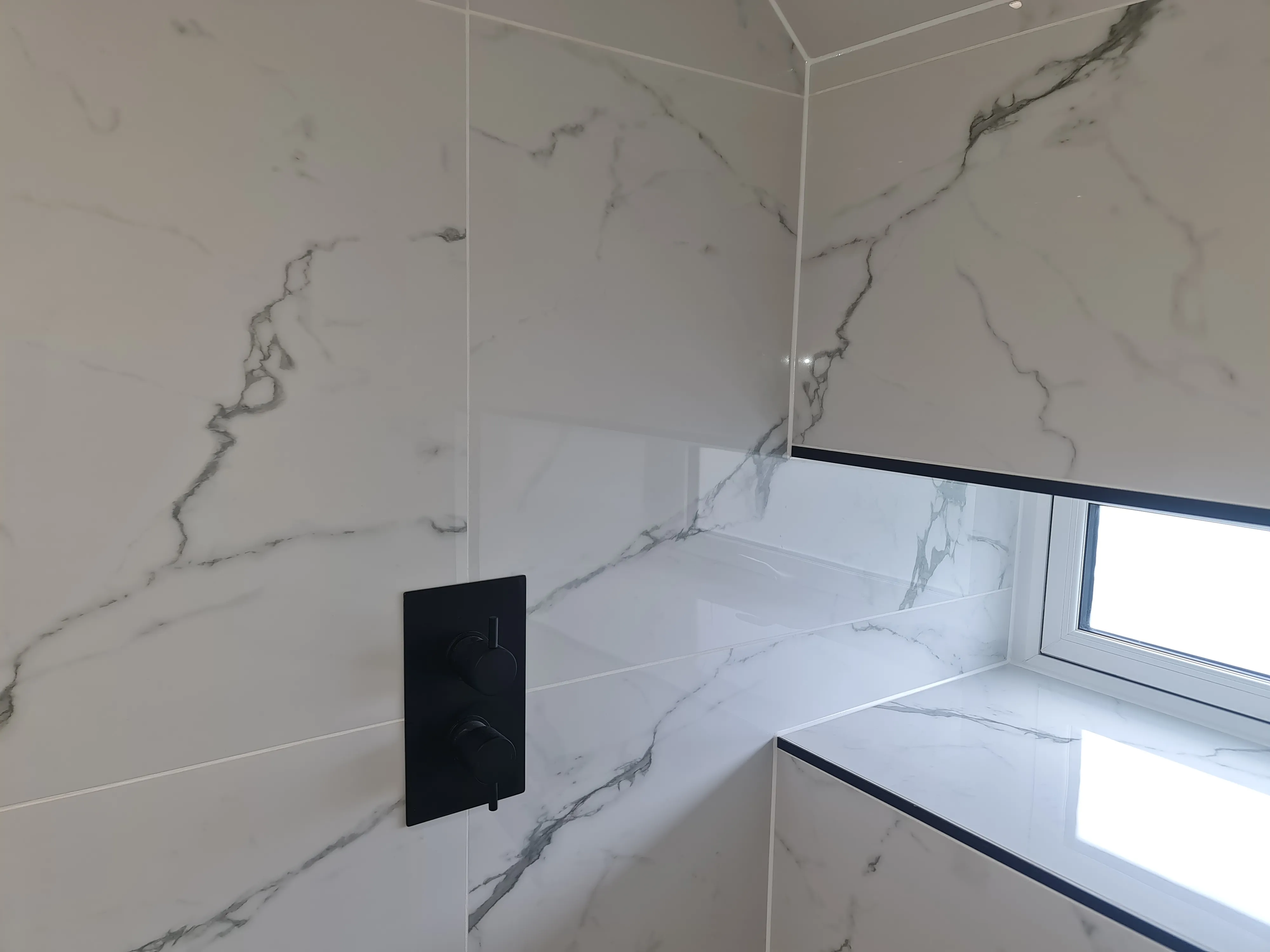 Bespoke luxury walk-in shower installation in Plymouth featuring marble-effect tiling and matte black fixtures by Sands & Vossen.