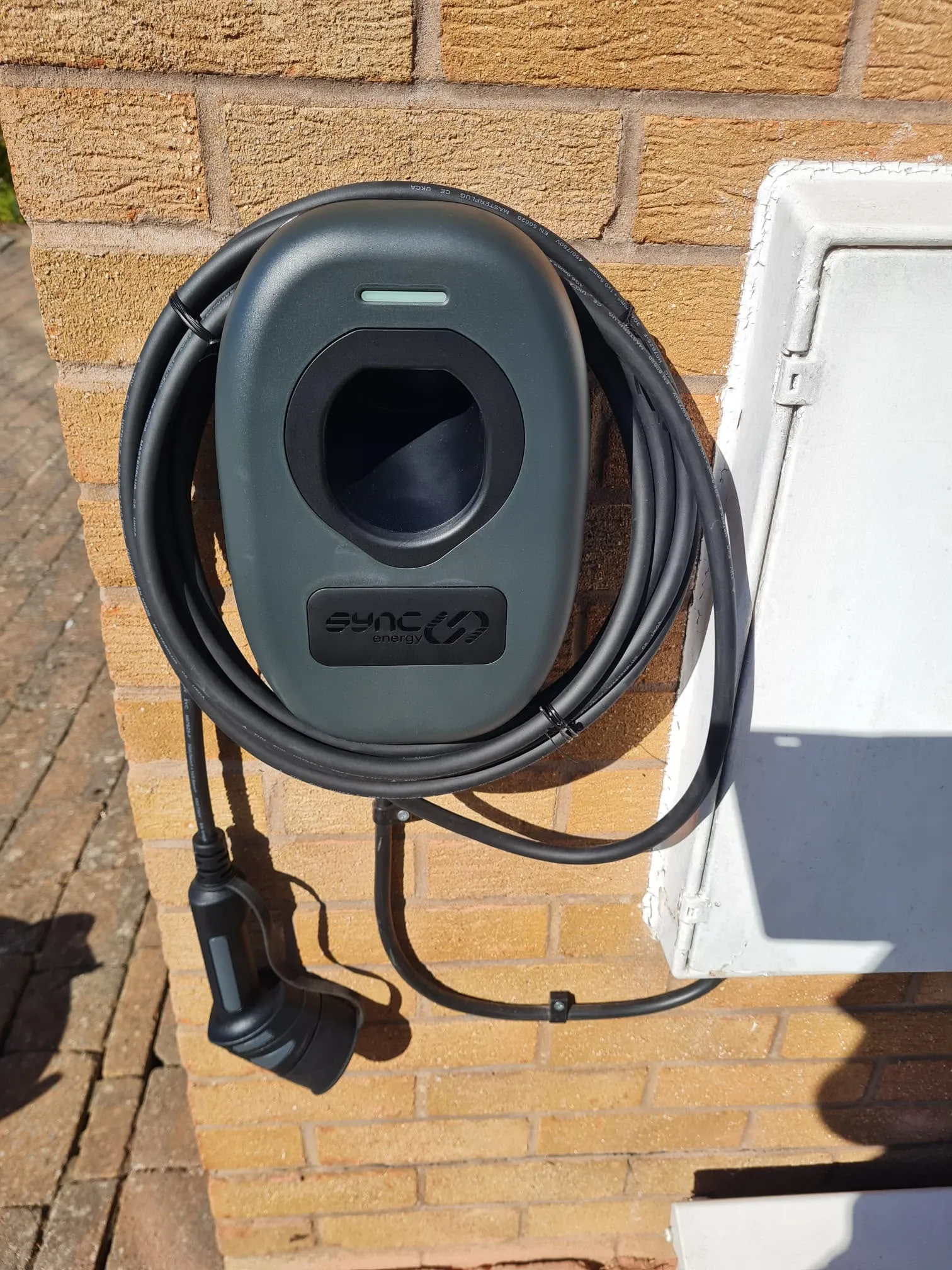 Sync Energy domestic electric vehicle charging point installed on an external brick wall