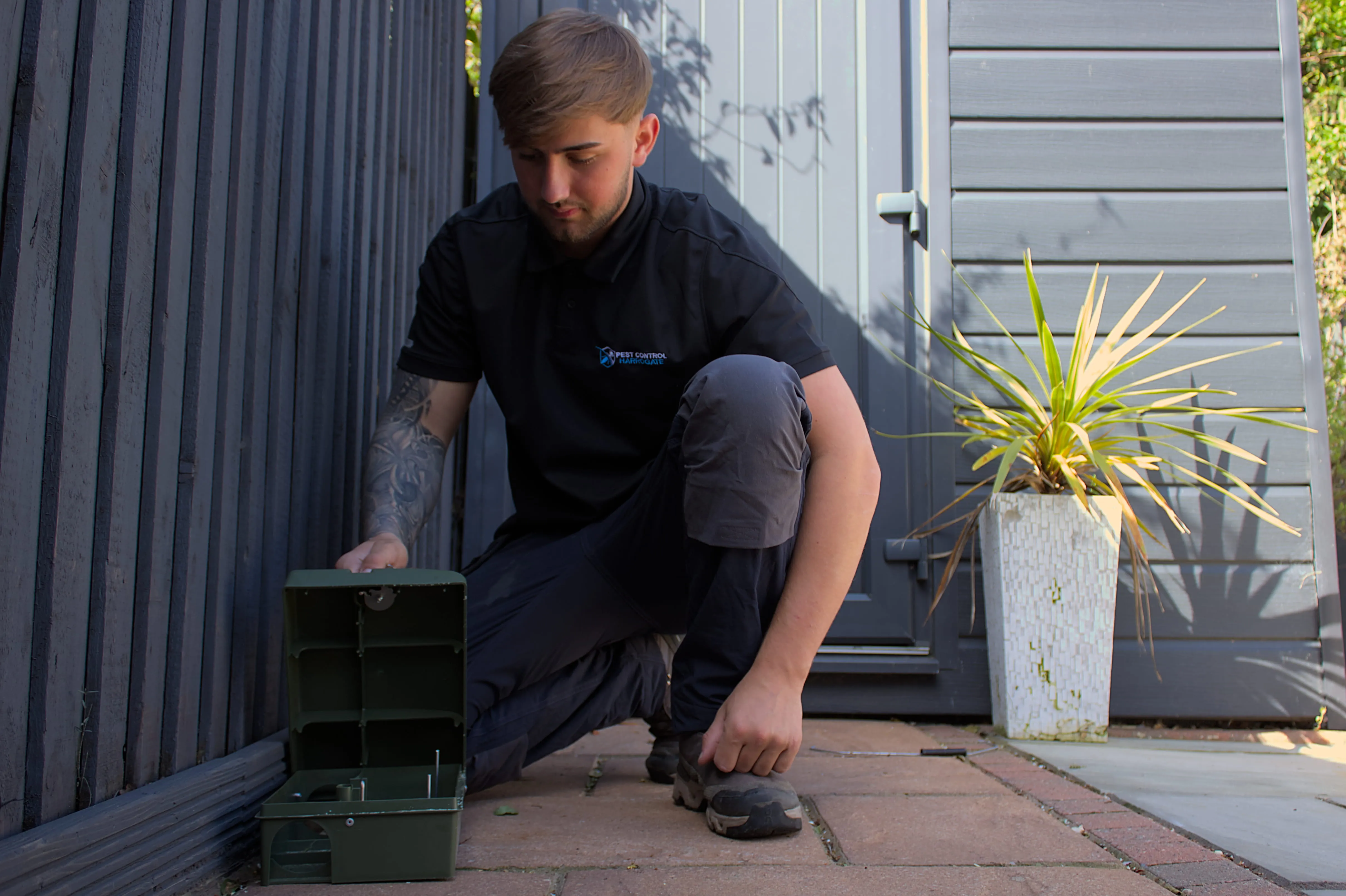 Professional pest control technician setting a rat bait station in a Harrogate garden
