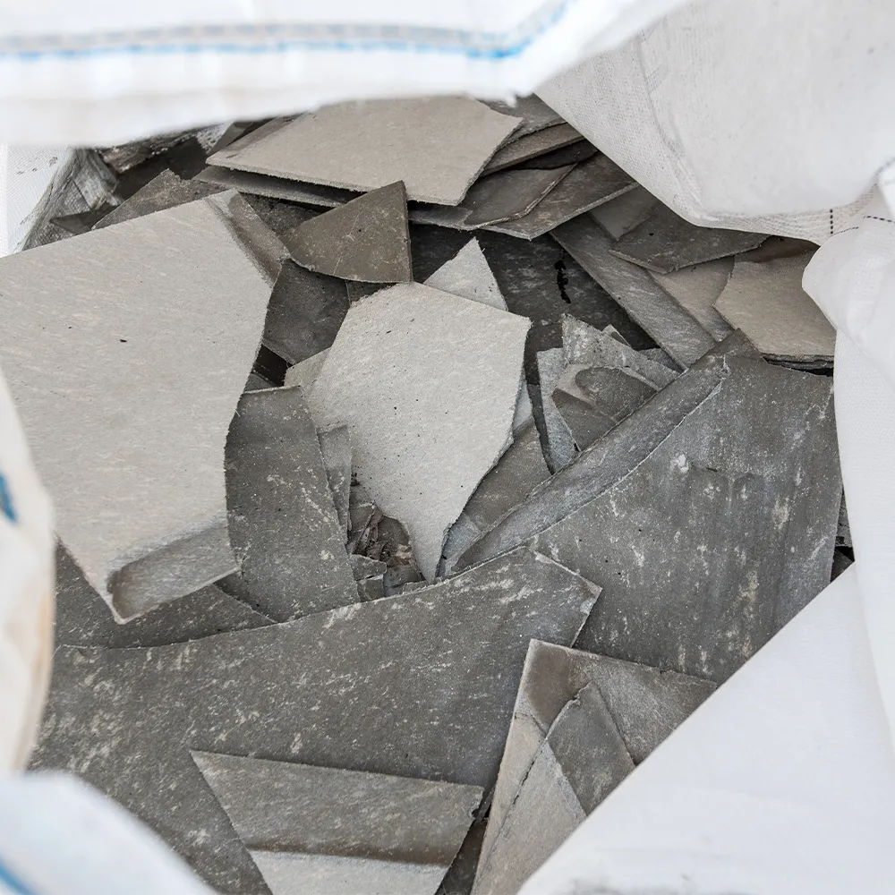 Asbestos cement fragments inside a white disposal bag for safe waste management