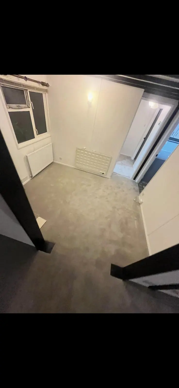 Newly renovated empty room with grey carpet, white walls, and exposed dark timber beams.