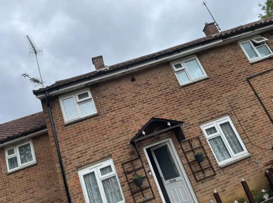 Exterior of a residential brick house showing a tiled pitched roof, chimney, and guttering