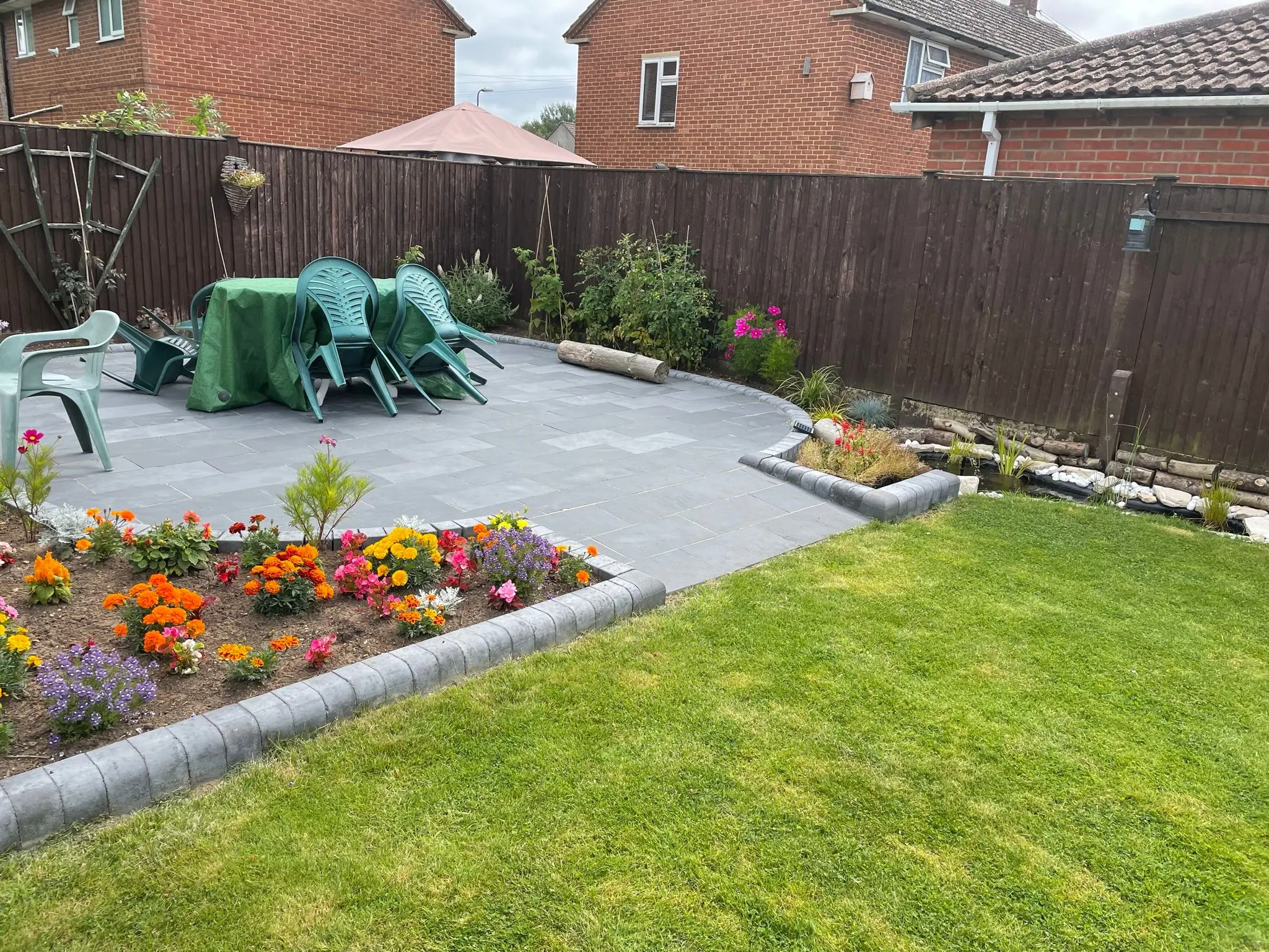 Beautifully landscaped residential garden featuring a newly installed grey porcelain patio with curved block edging