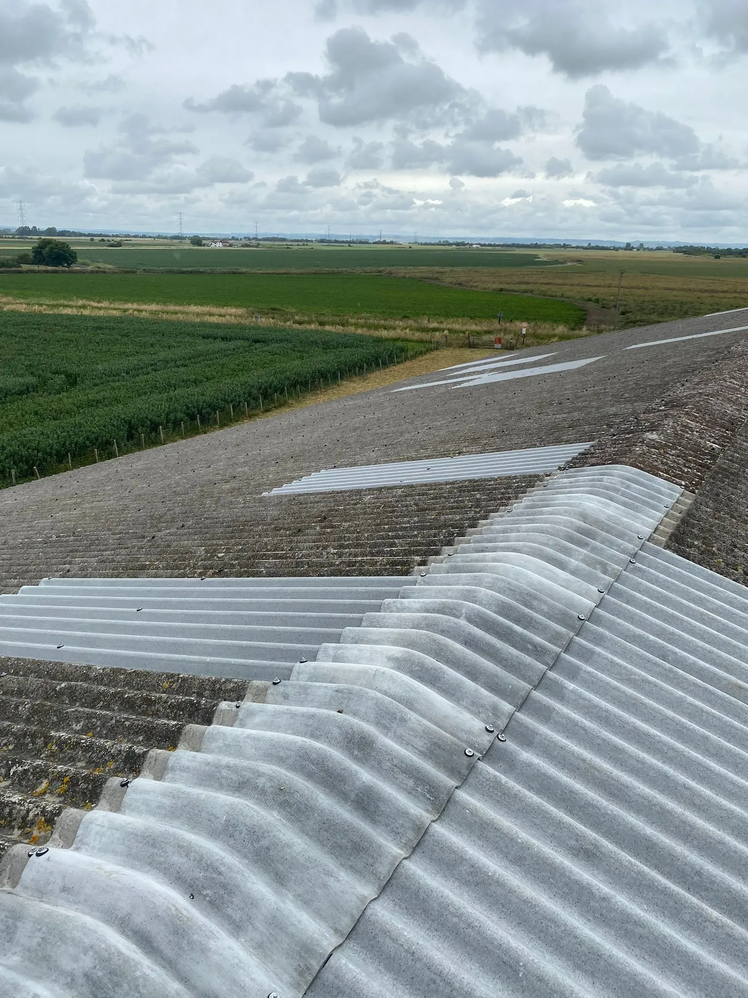 Newly installed corrugated roofing sheets and ridge caps repairing an agricultural barn roof in Sussex