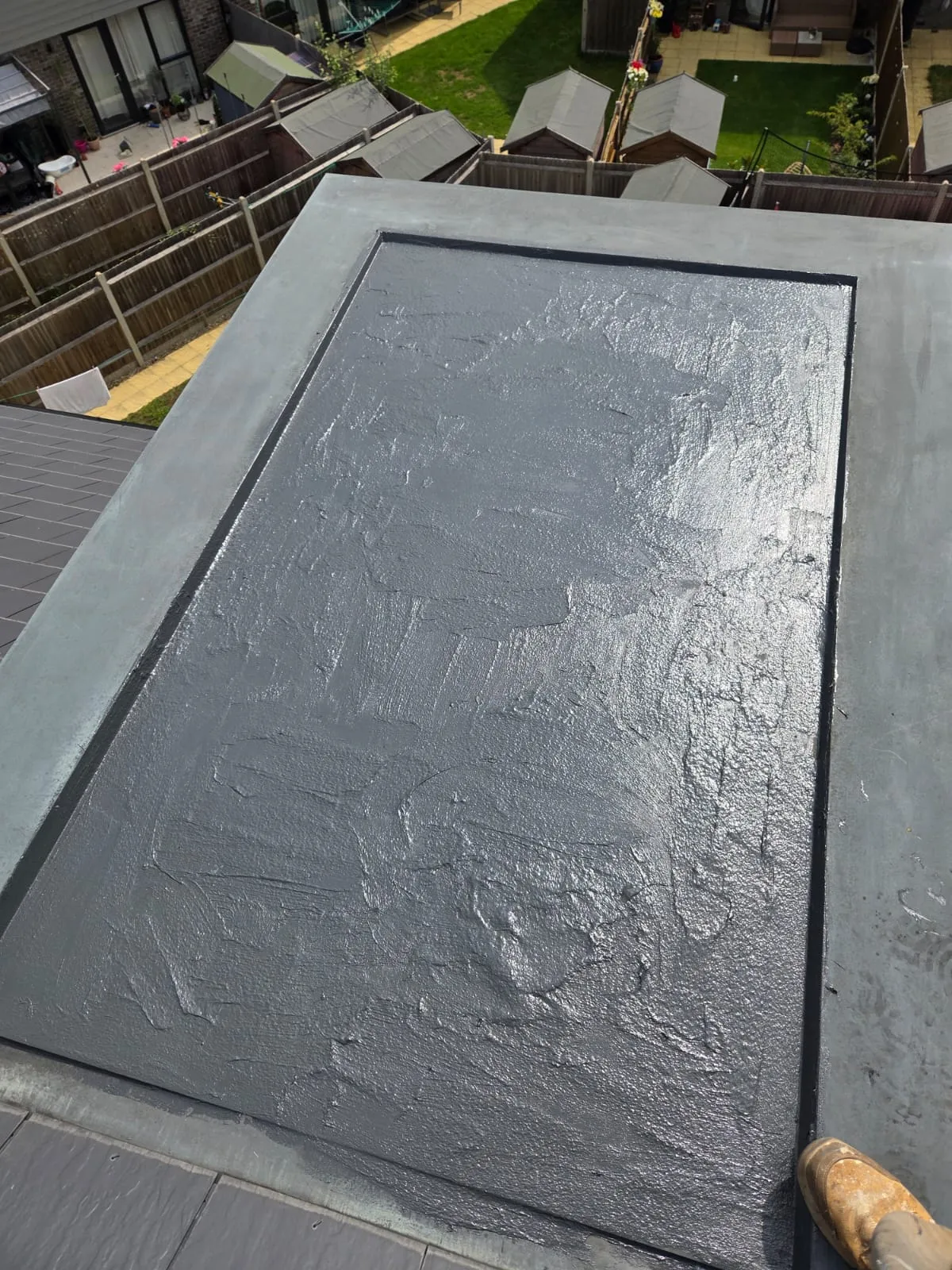 Professional flat roof installation showing a grey waterproof membrane on a domestic property.