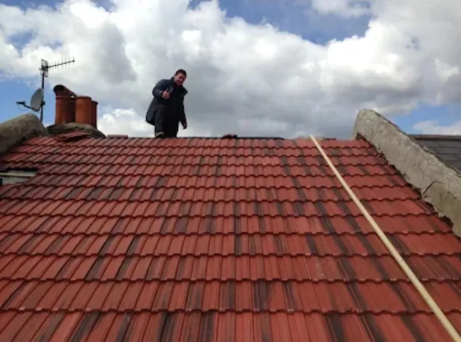 Roofer carrying out an inspection on a red-tiled pitched residential roof