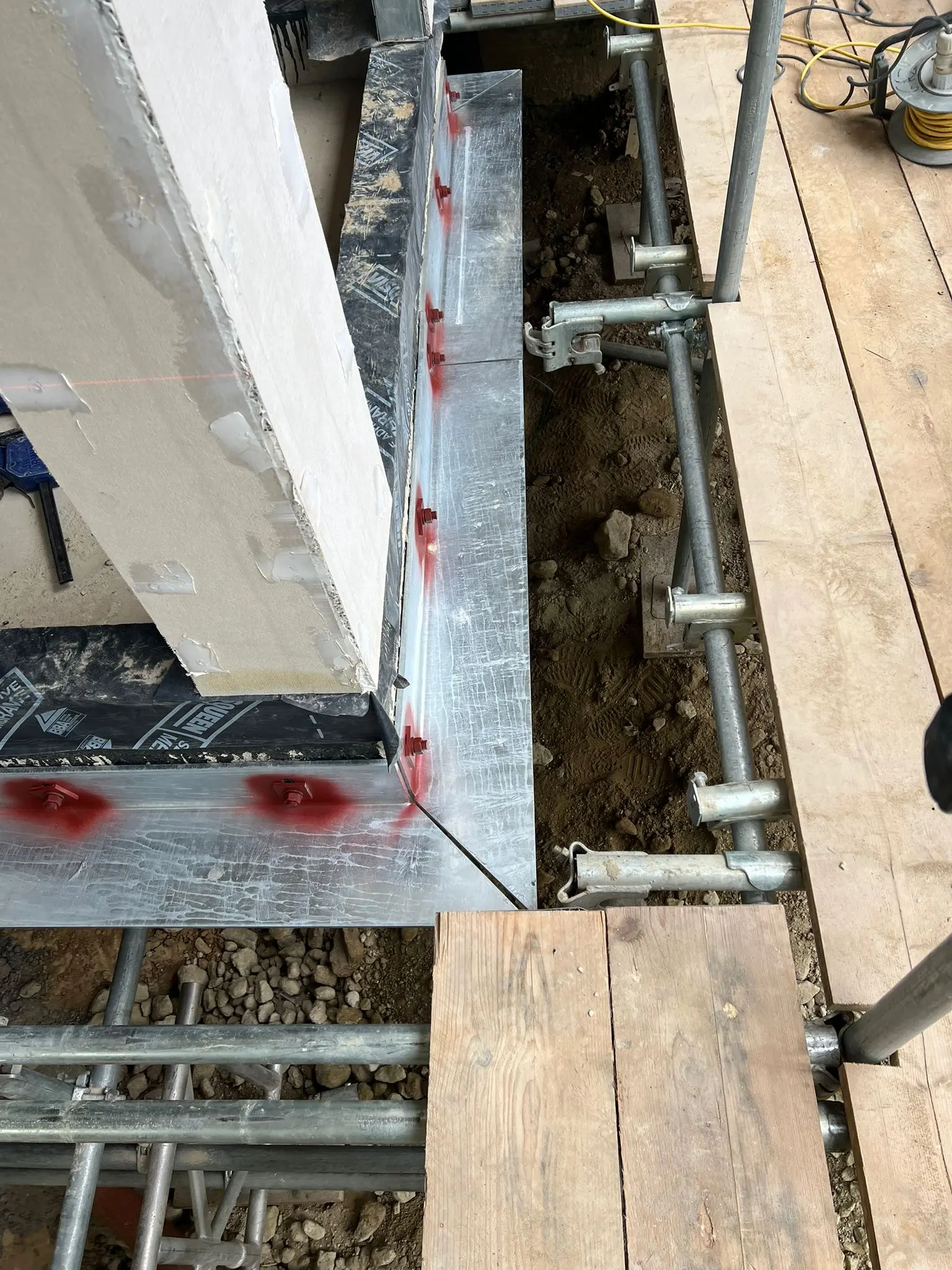 Close-up of structural foundation groundworks, base fixings, and damp proofing membrane during commercial construction by ER3 Group LTD.