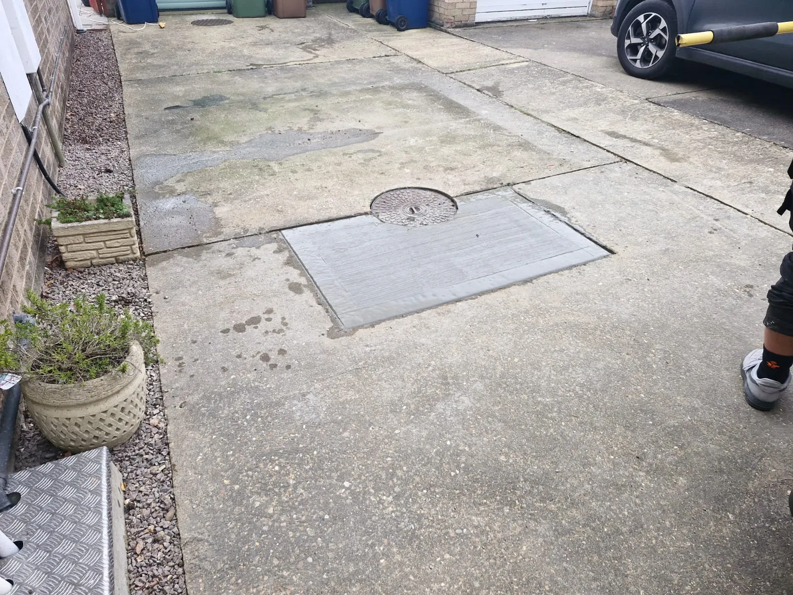 Professional concrete patch repair around a manhole cover on a residential driveway by Roberts Drainage Ltd.