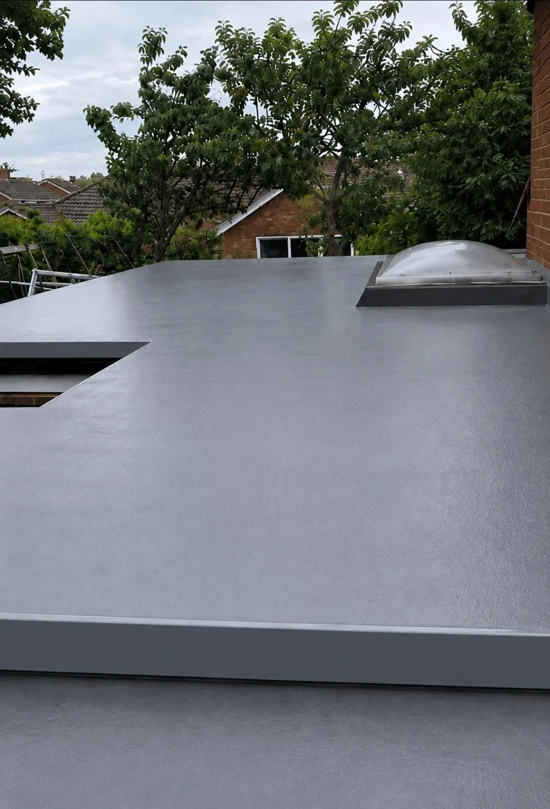 Seamless grey GRP fibreglass flat roof installation with skylight on a domestic property