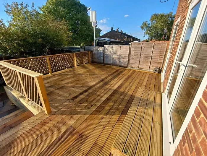 Newly installed wooden decking with decorative lattice railings, steps, and a modern design, providing an inviting outdoor living space next to a home in Canterbury, Kent.