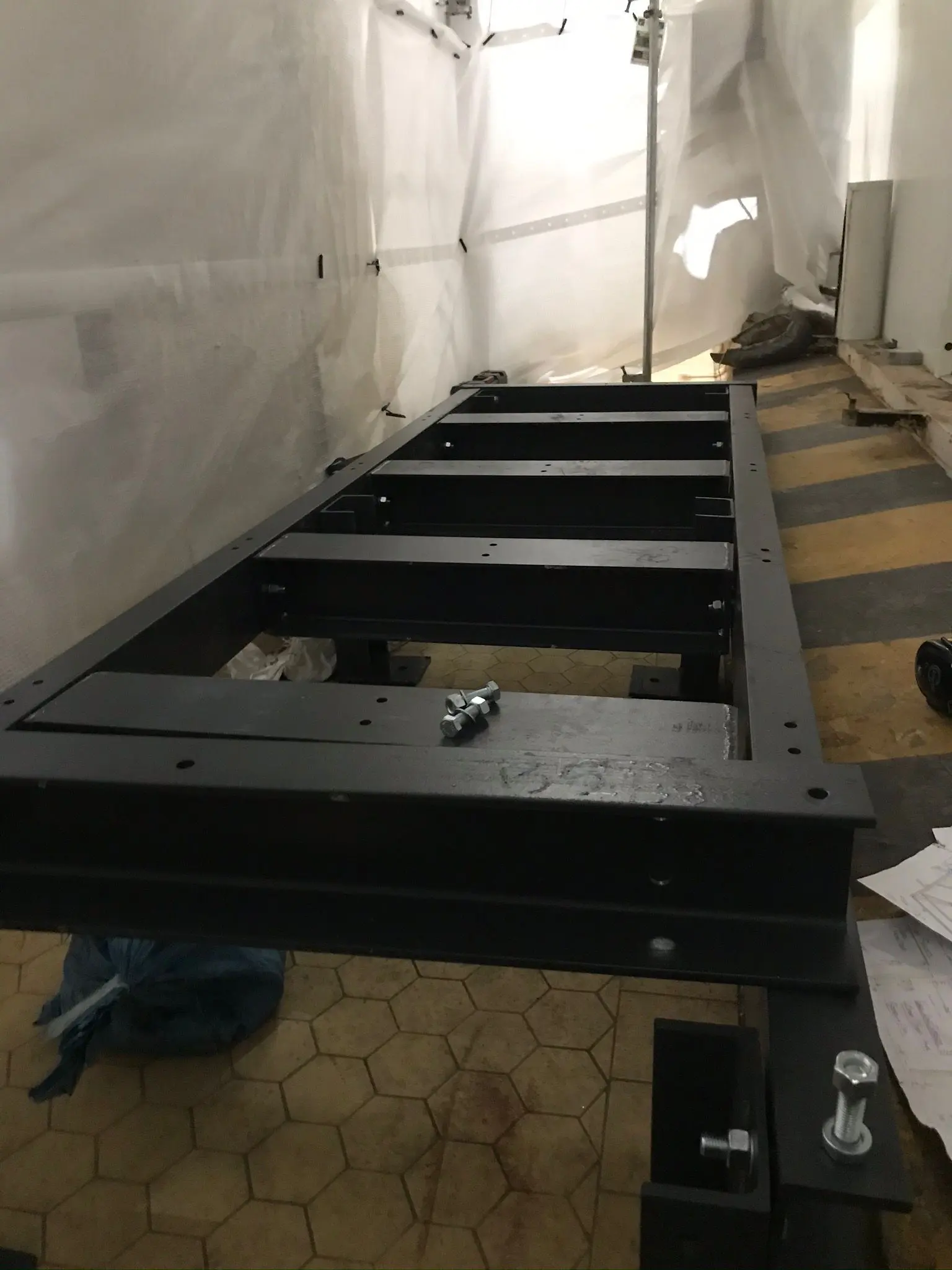 Structural steel frame section being assembled with bolts and technical drawings for a commercial build