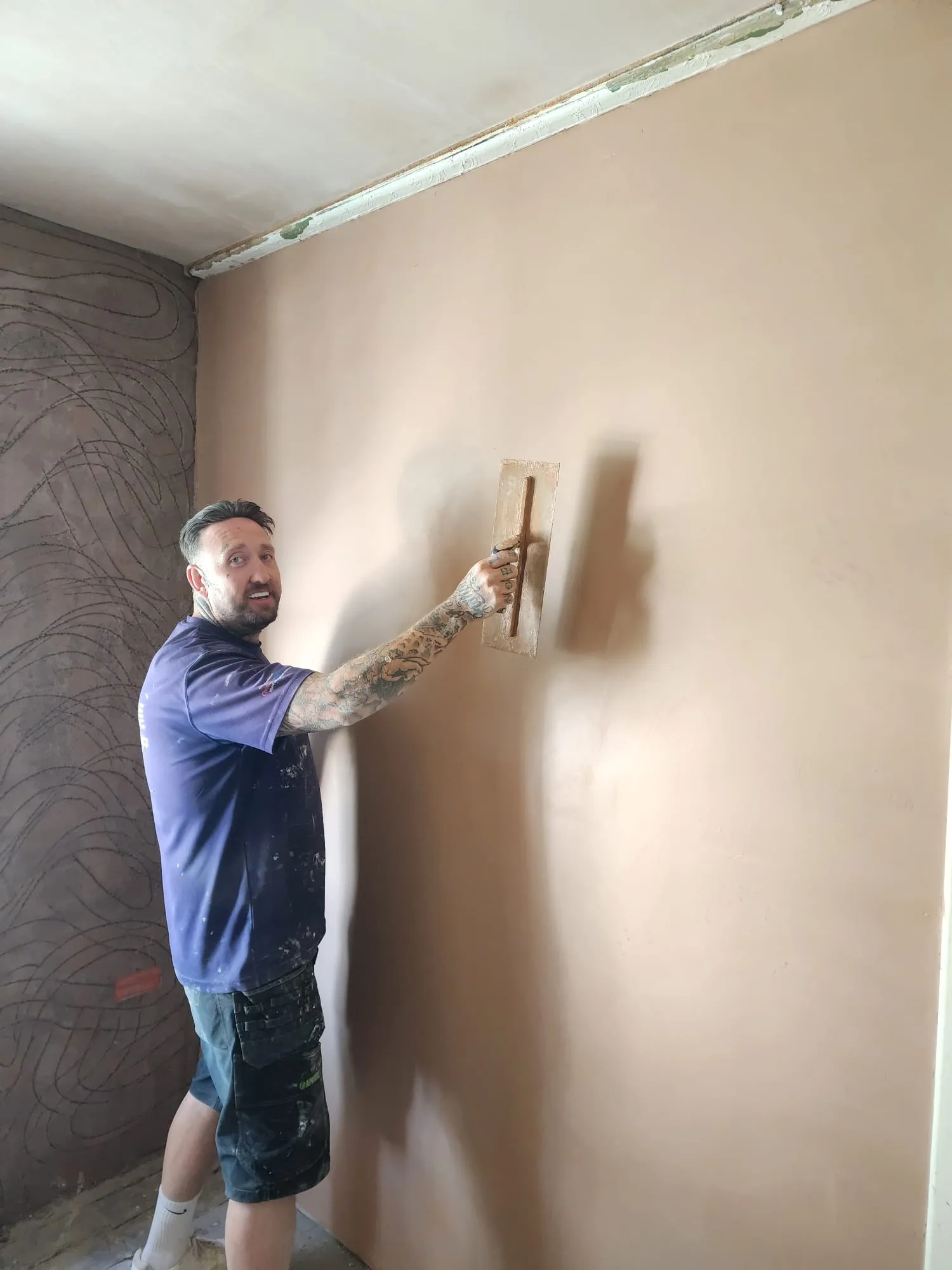 Professional plasterer skimming an internal wall with a trowel