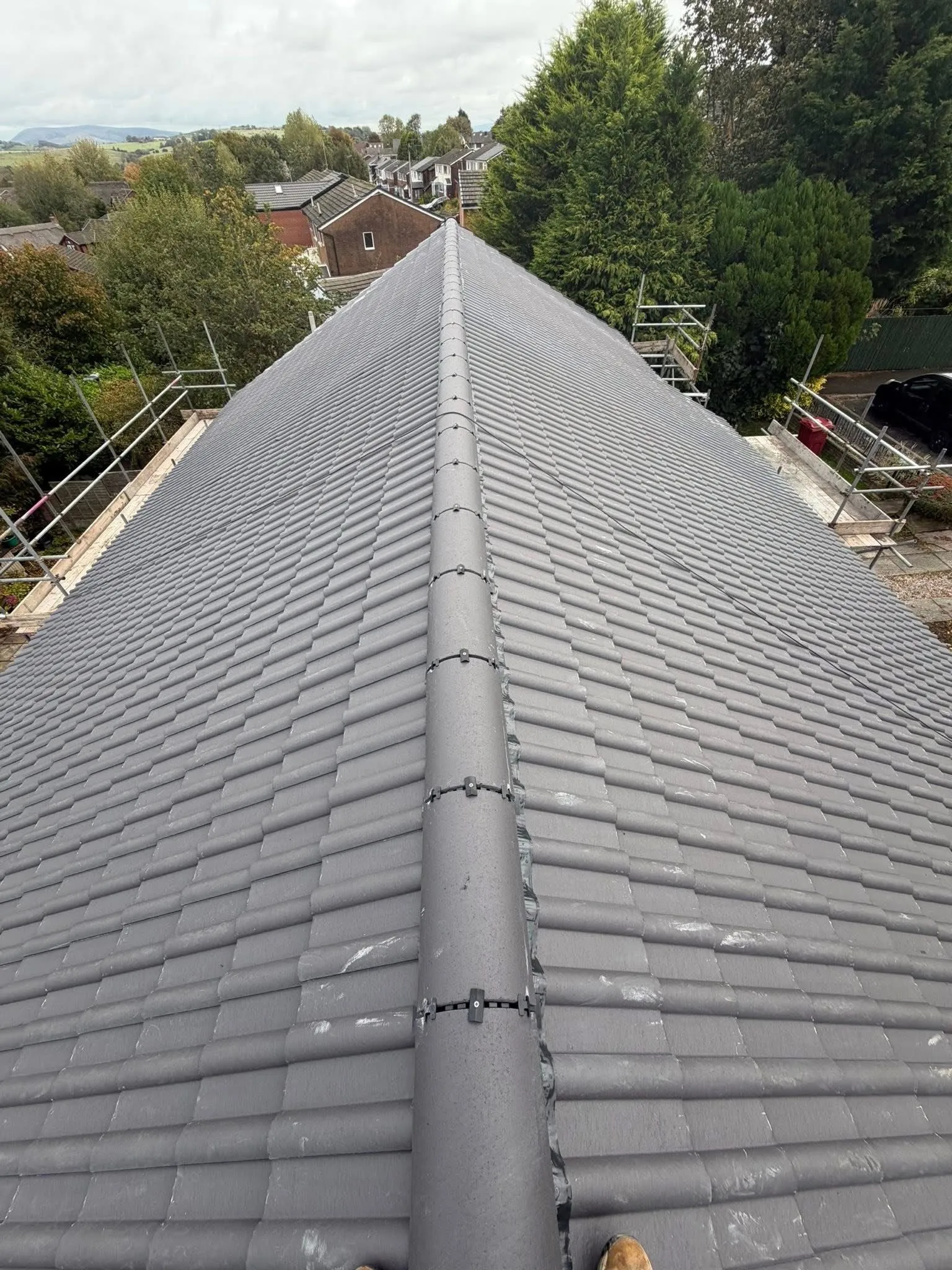 Newly installed grey tiled pitched roof with dry ridge system by Lancashire Roofing Specialist in a residential area.