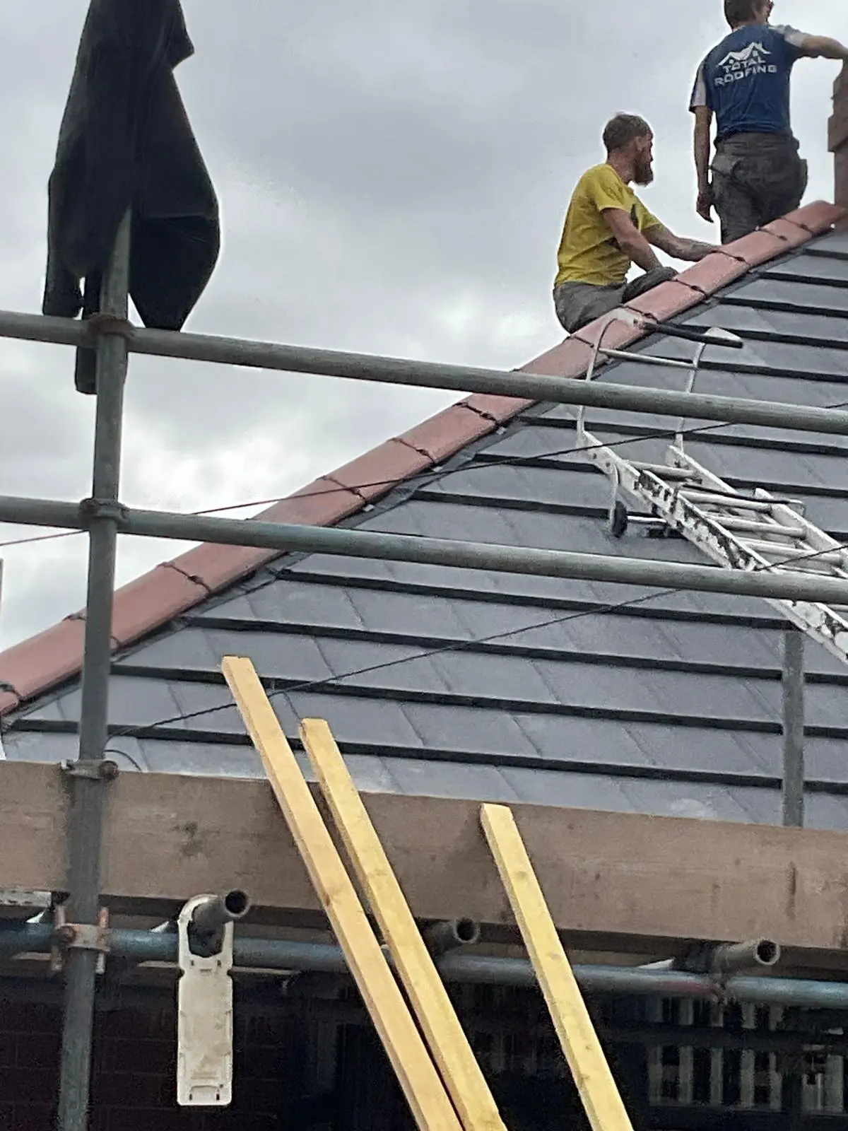 Professional roofers installing a new pitched tile roof on a house