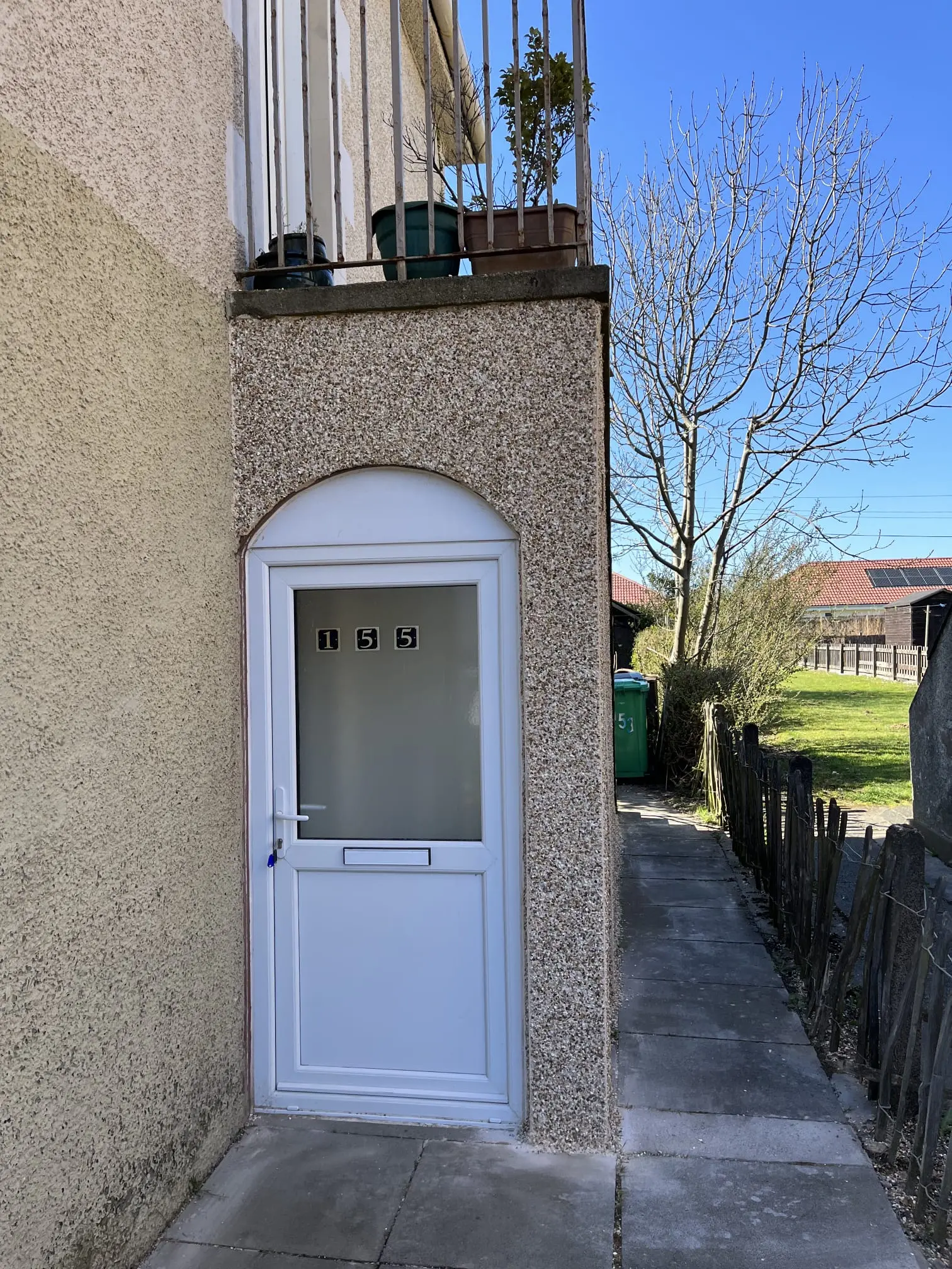 A close-up of roughcast rendering around a white UPVC front door on a Scottish residential property