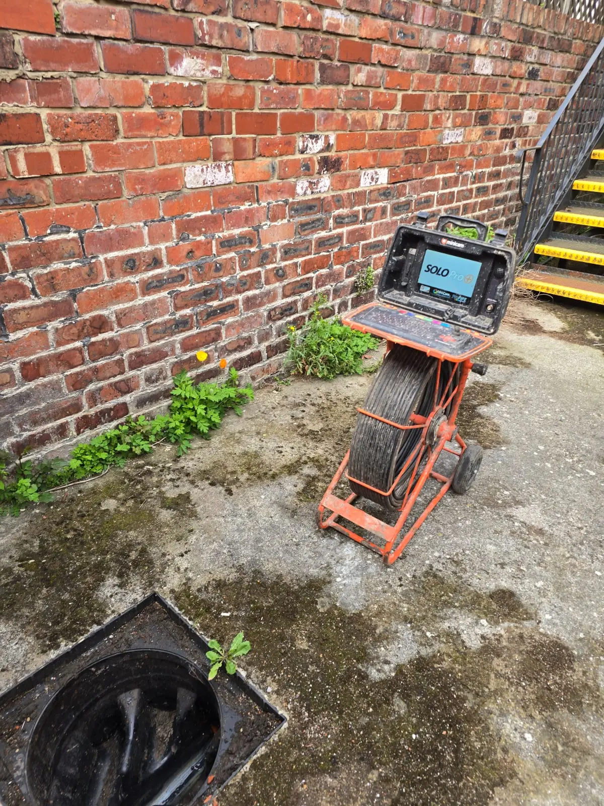 Minicam Solo Pro+ CCTV drain survey equipment positioned next to an open inspection chamber ready for a structural drain inspection.
