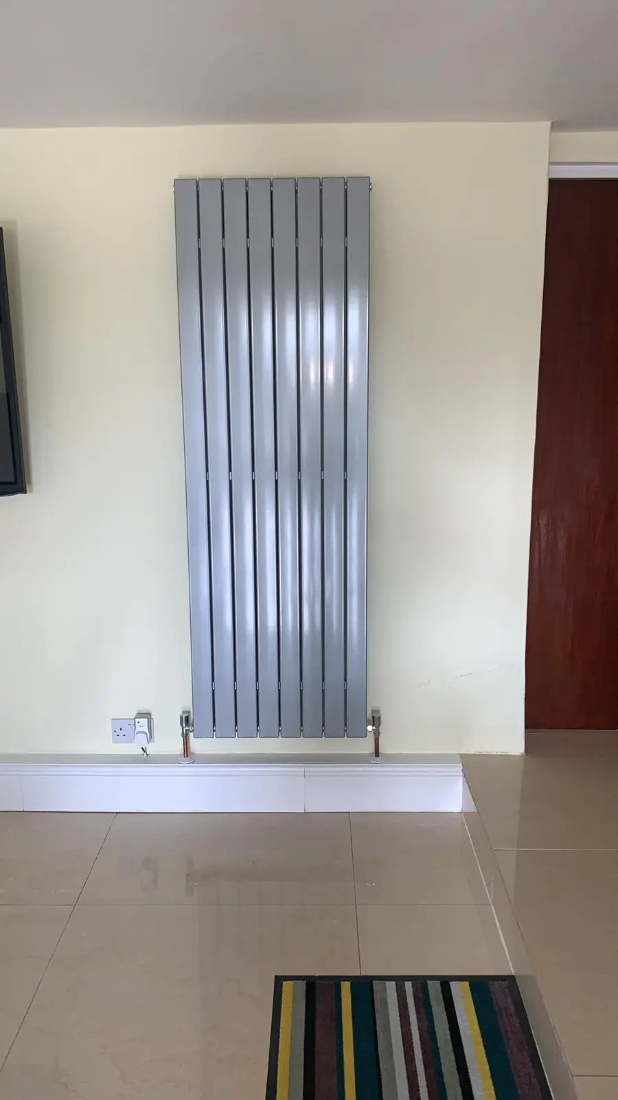 Modern vertical silver designer radiator installation in a Bolton home