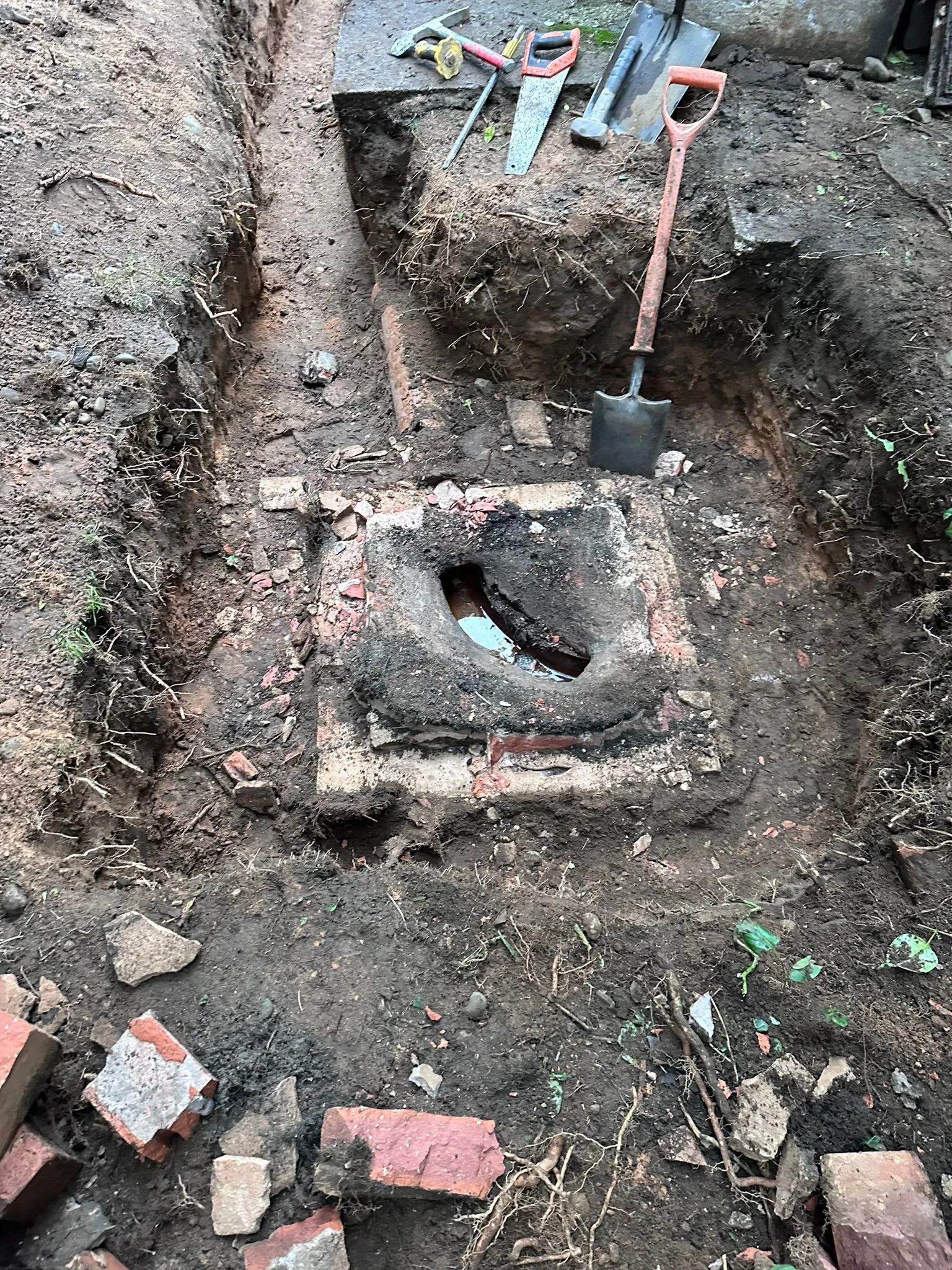 Drain excavation and repair work uncovering an old brick manhole in Macclesfield