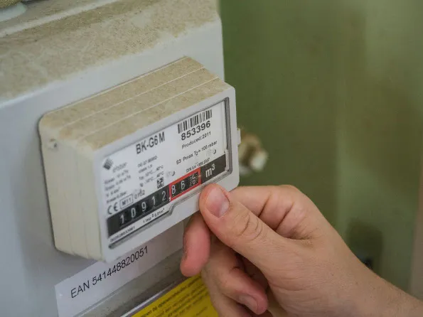 A hand checking a domestic gas meter reading during an EPC assessment