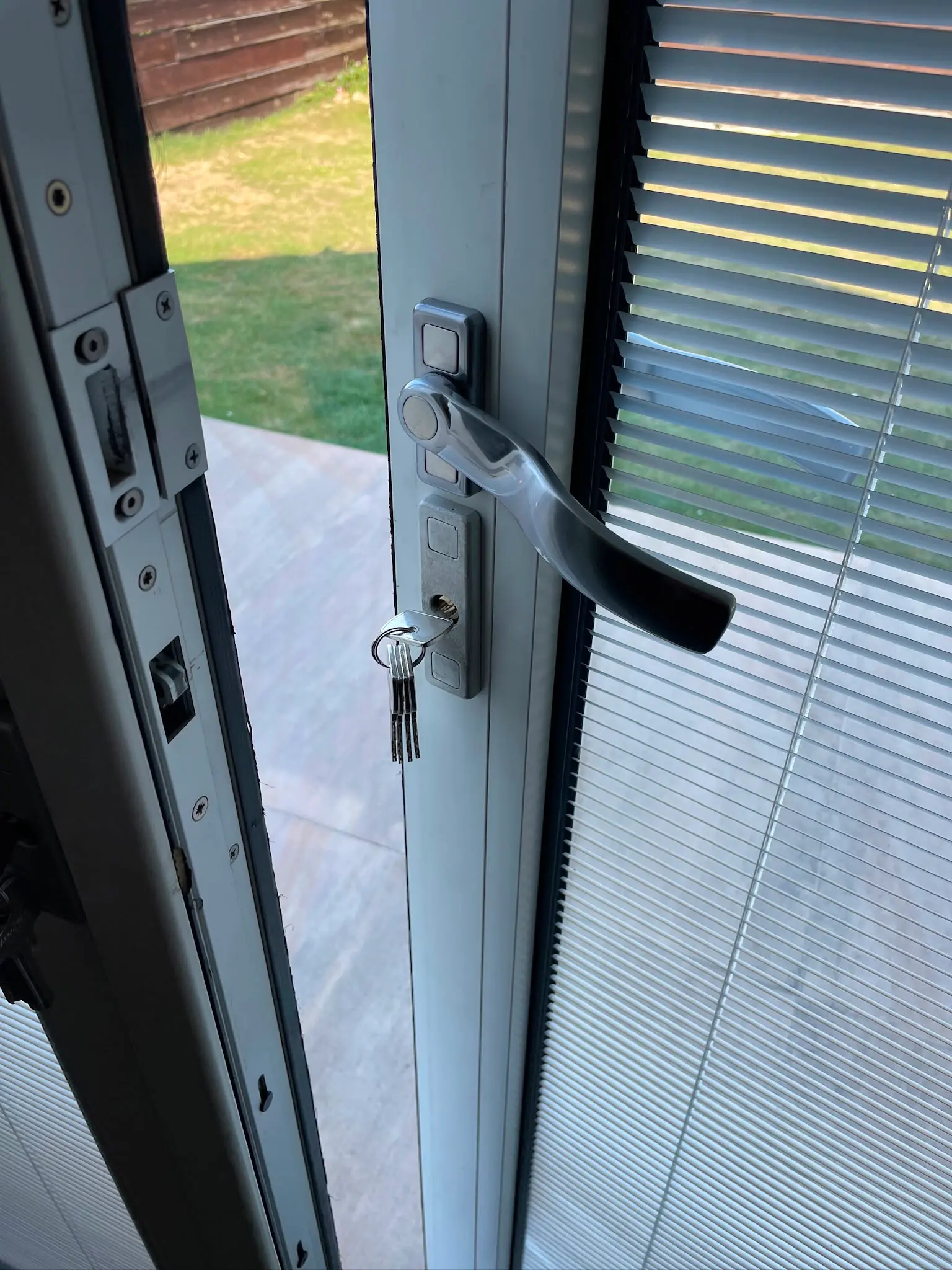 Close-up of a white uPVC door showing a silver handle, keys in a euro cylinder lock, and the multi-point locking strip.